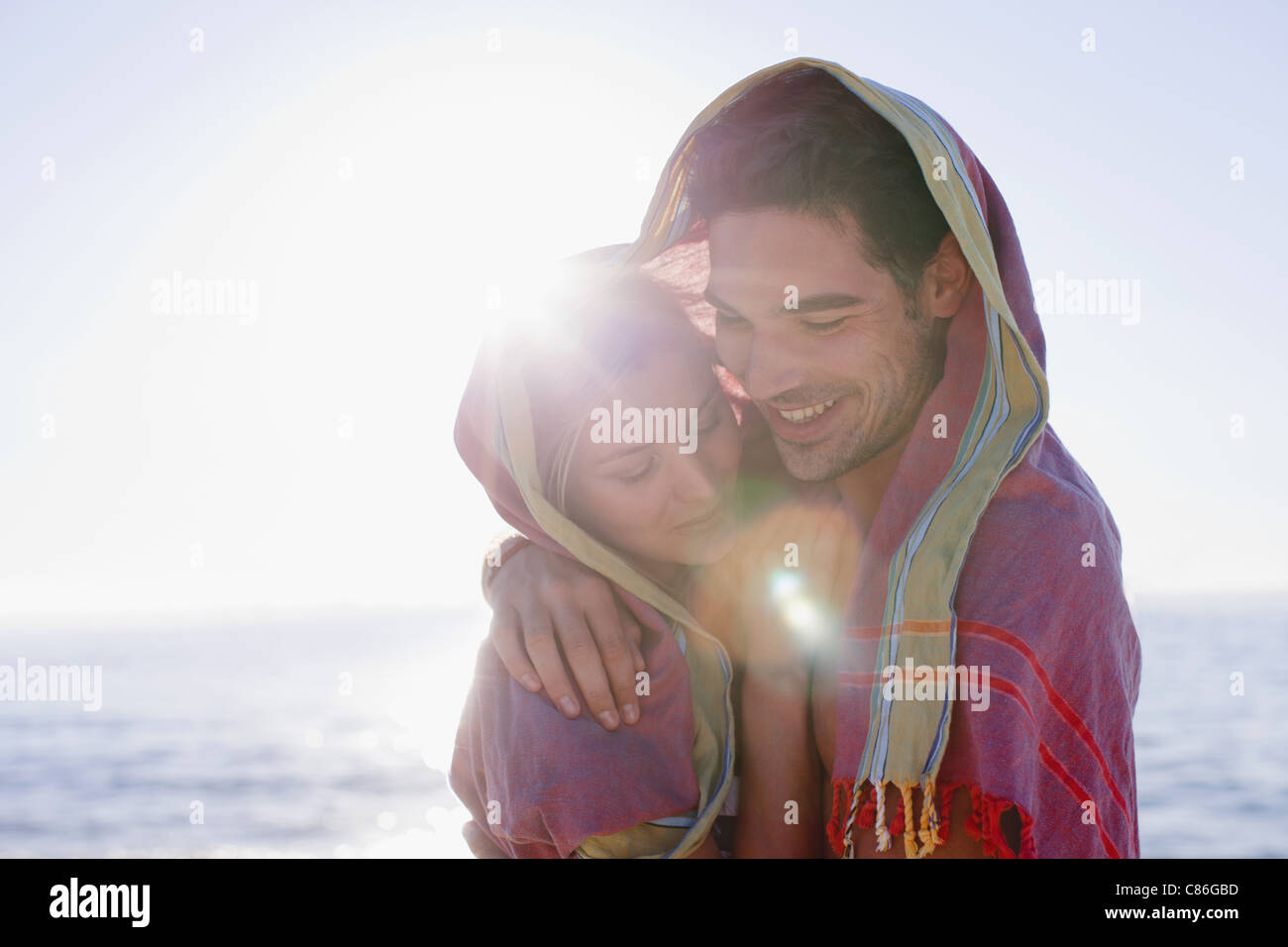 Couple hugging under blanket on beach Stock Photo - Alamy