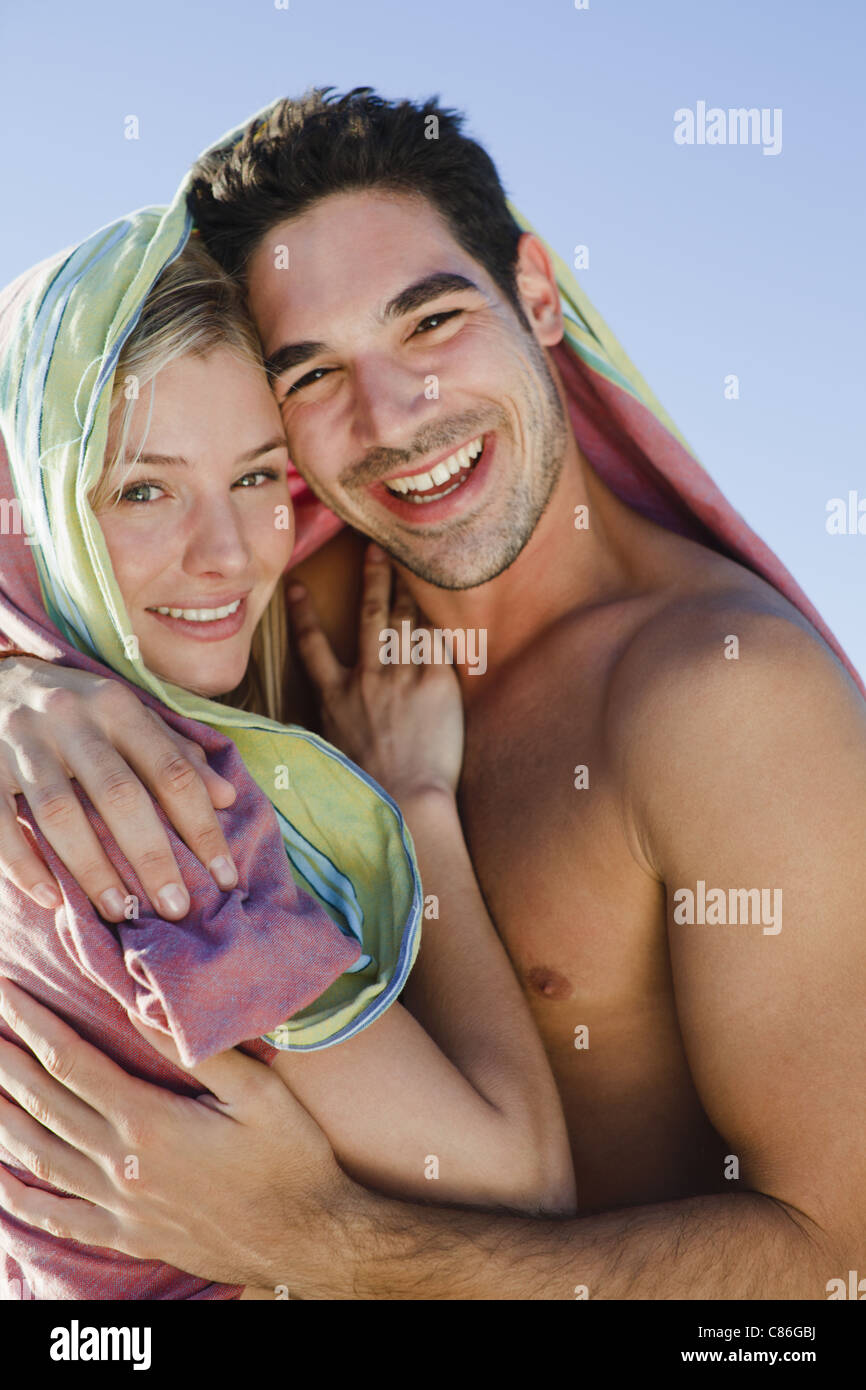 Couple hugging under blanket on beach Stock Photo - Alamy