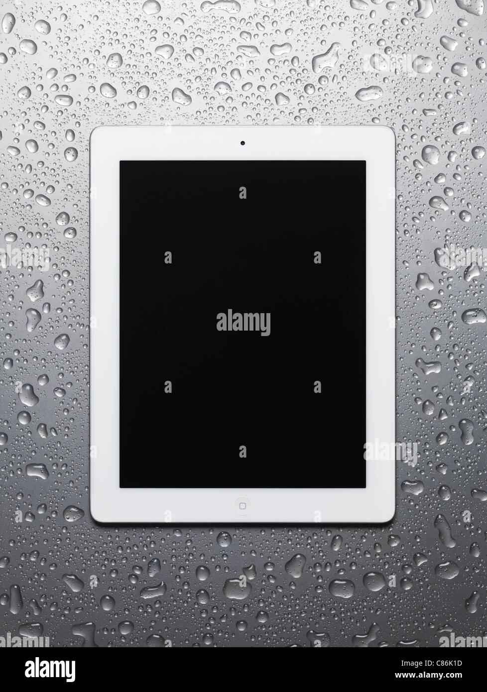 White Apple iPad 2 tablet computer with blank screen on wet gray steel background Stock Photo