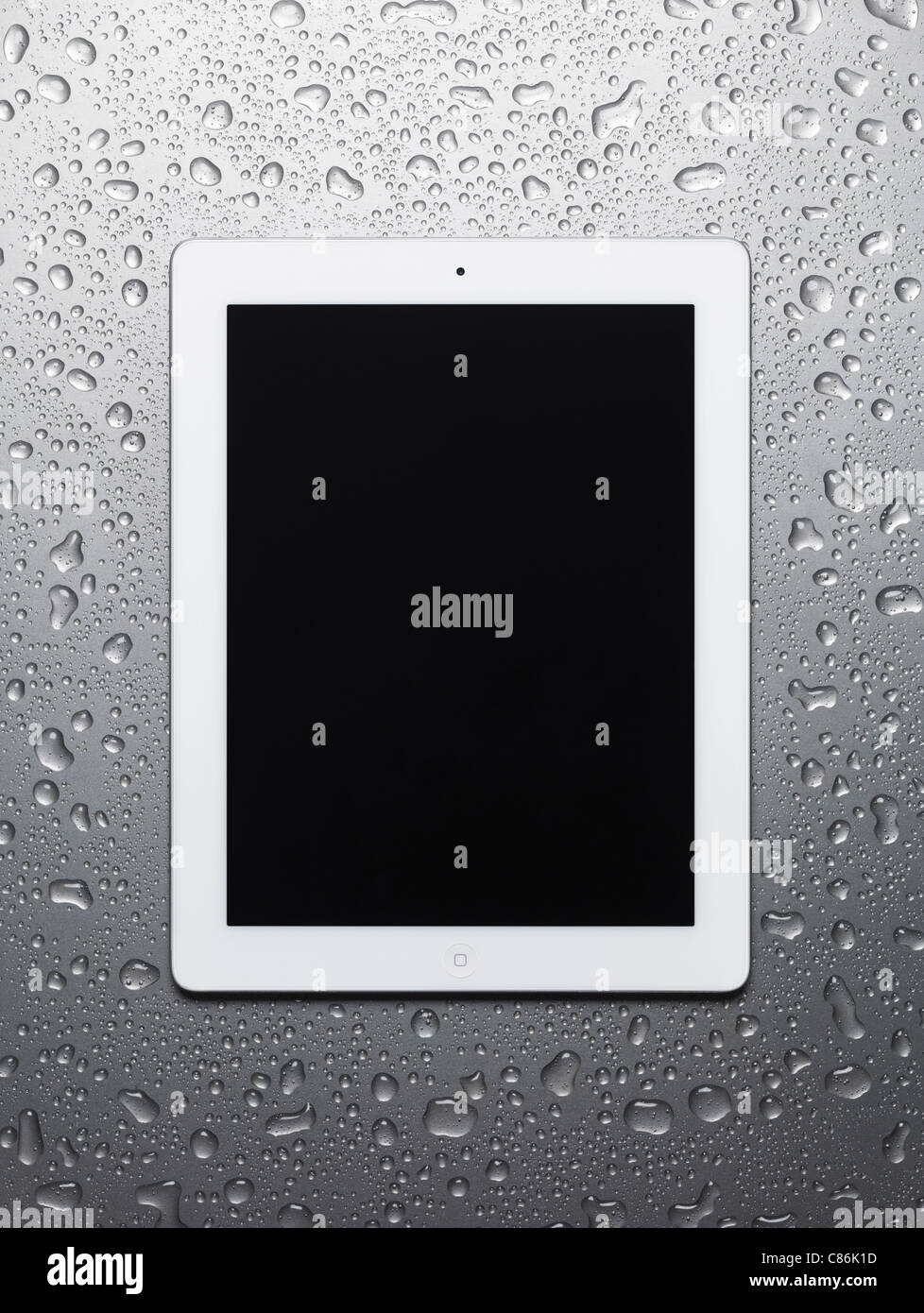 White Apple iPad 2 tablet computer with blank screen on wet gray steel