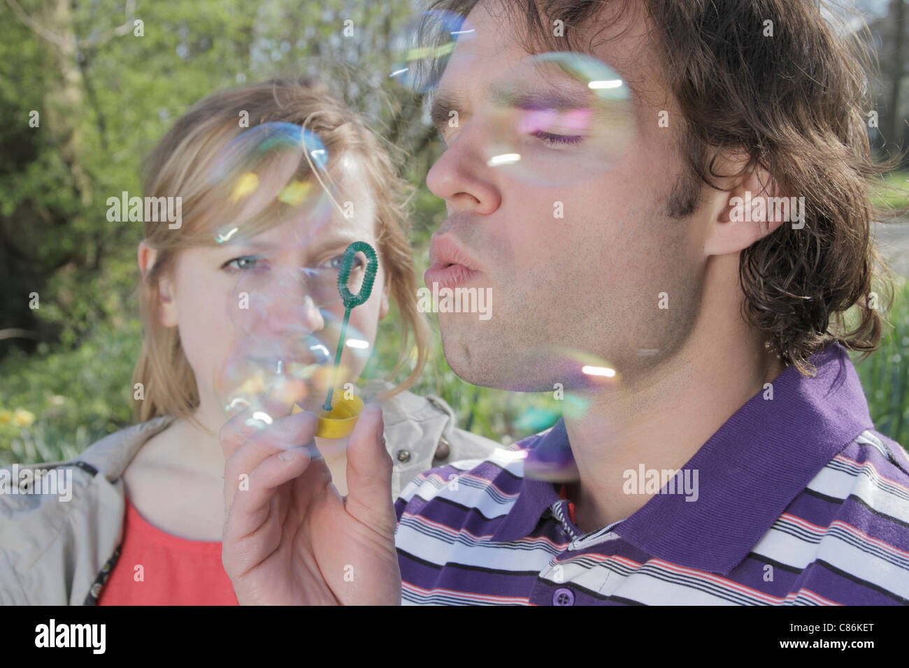 Couple blowing bubbles in park Stock Photo