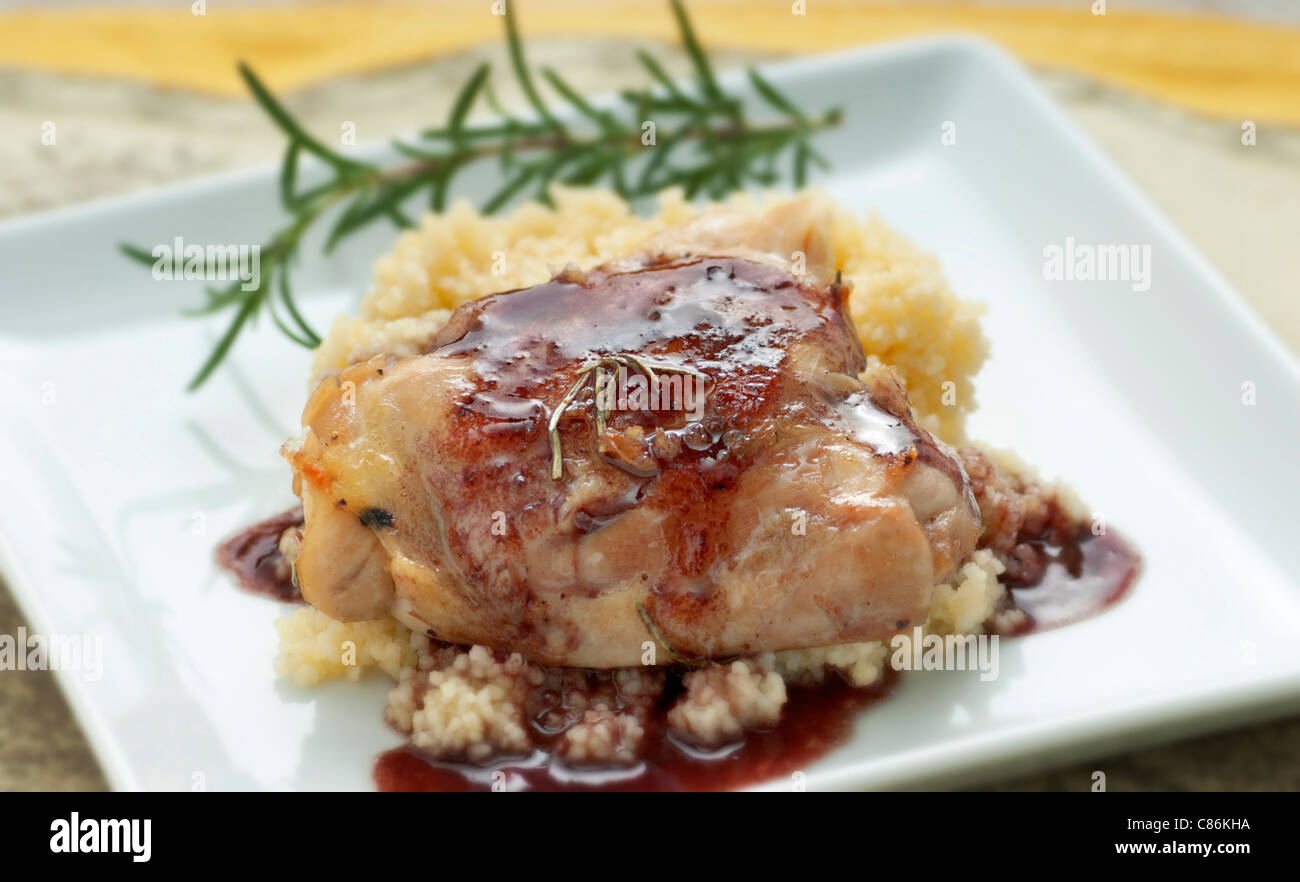 Chicken over golden cous cous with red wine sauce and rosemary garnish Stock Photo