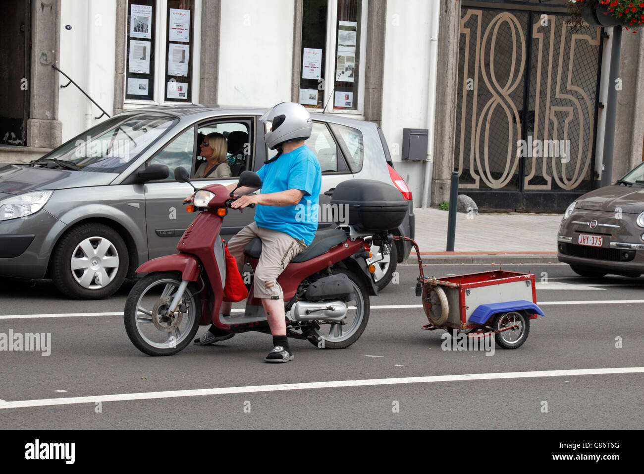 Casually dressed man on a Honda motor scooter with attached trailer in the town of Waterloo, Belgium. Stock Photo