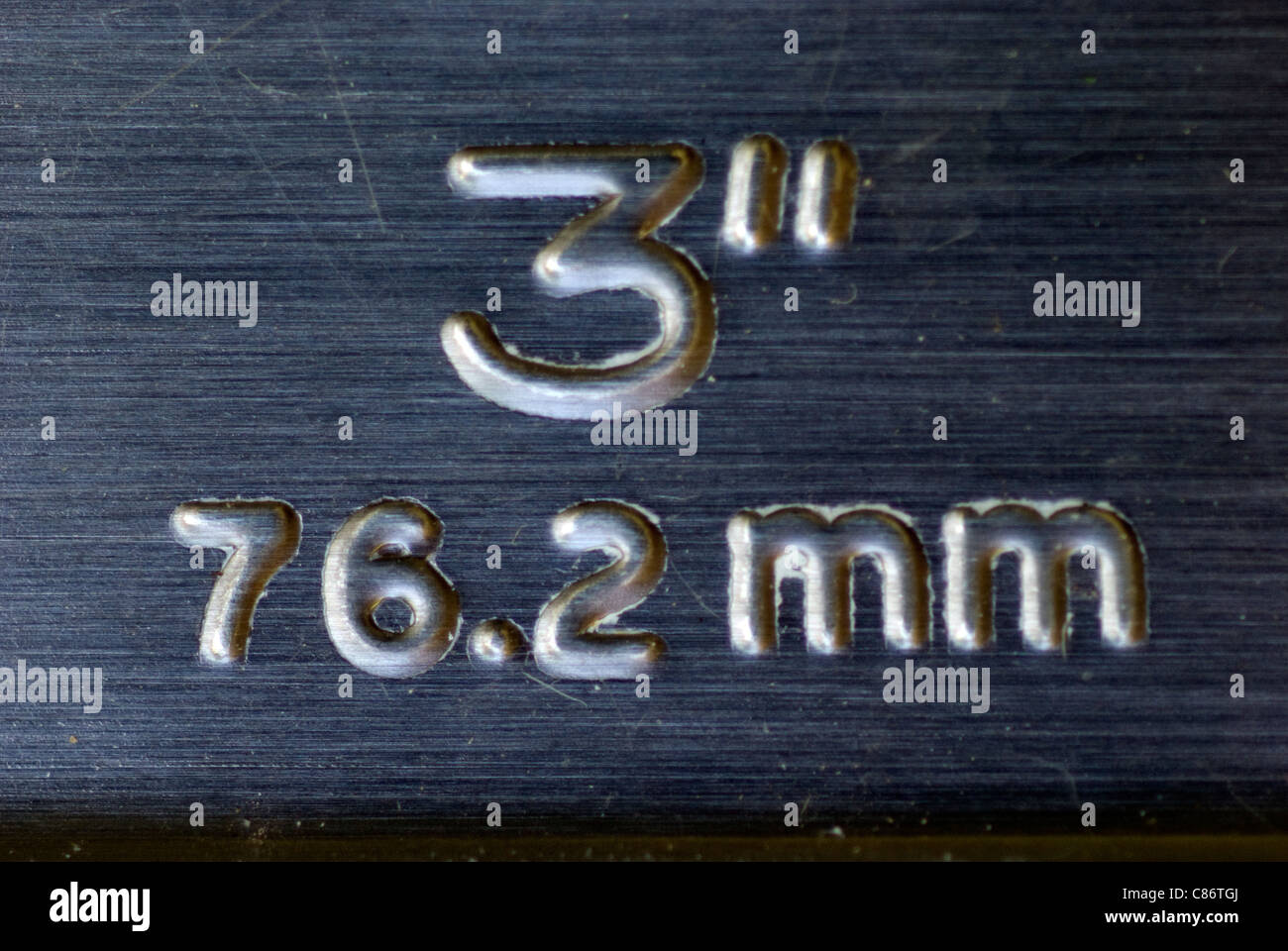 Stamped and embossed metal lettering detailing the dimensions of a wide paintbrush. Stock Photo