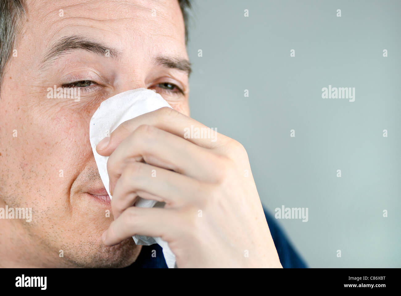 Close-up of a man holding a tissue on his nose. Stock Photo