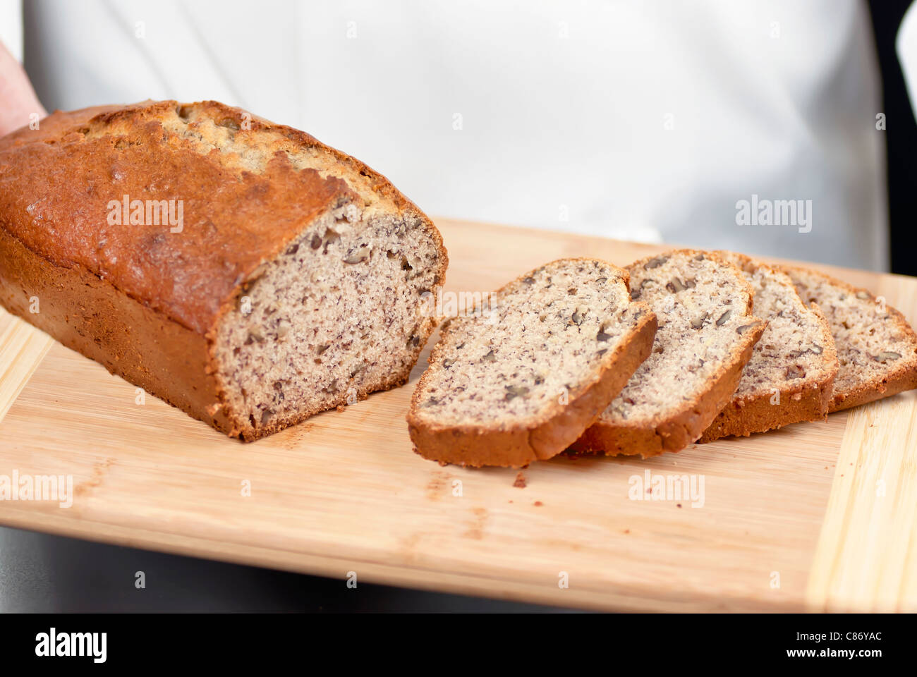 Close-up of sliced banana bread with a chef standing in the background. Stock Photo