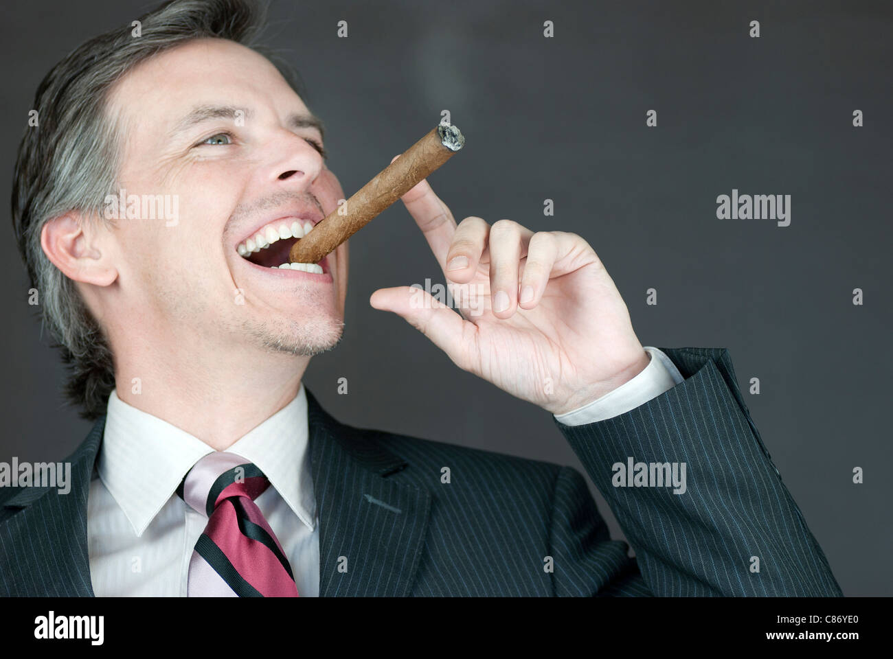 Close-up of a businessman celebrating with a cigar, side view. Stock Photo