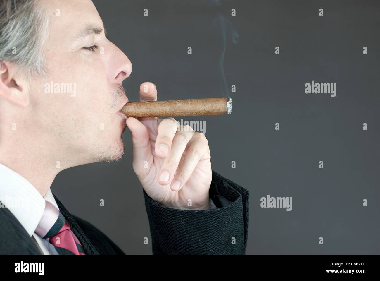 Close-up of a businessman smoking a cigar, side view. Stock Photo