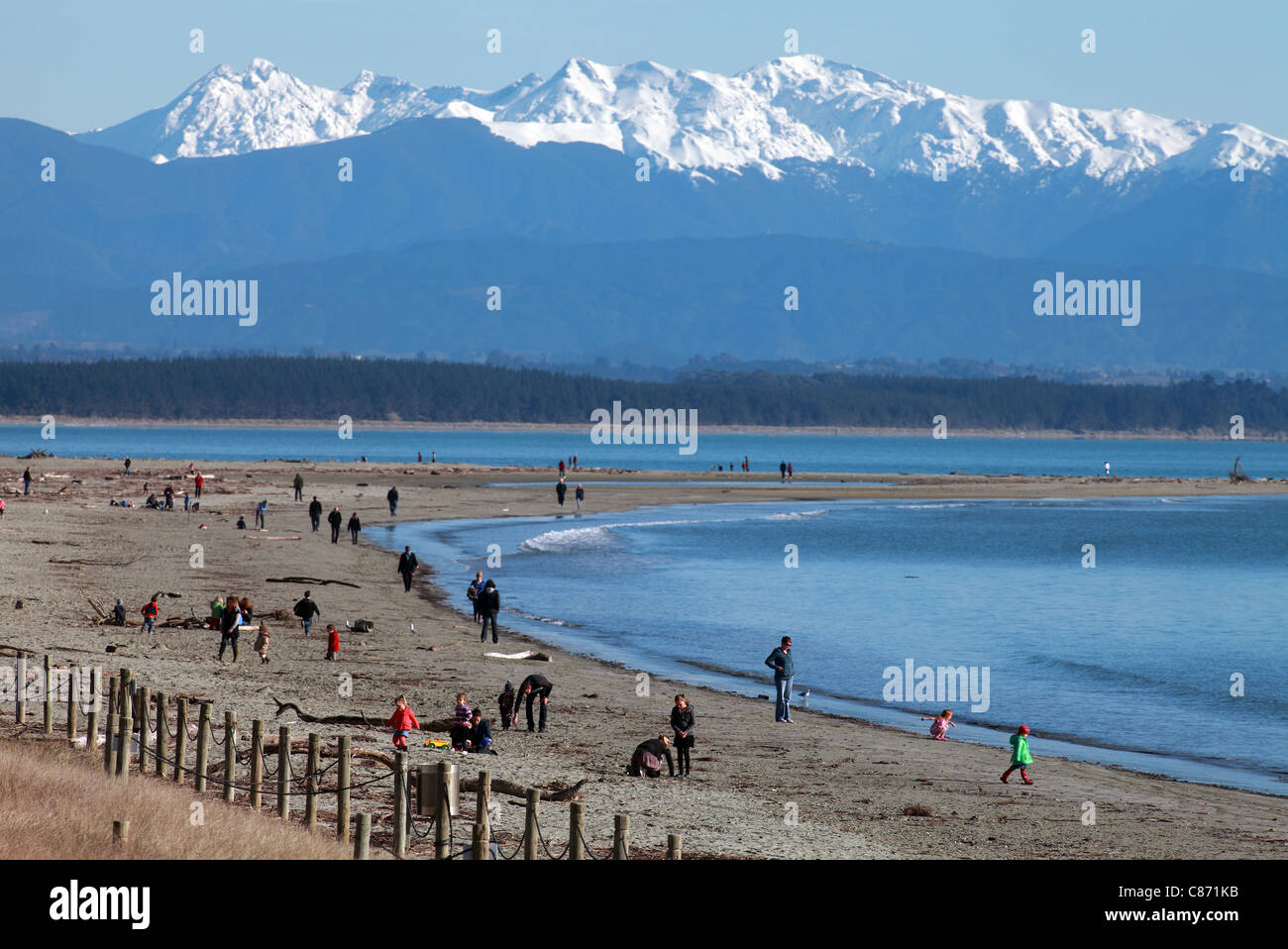 Winter Walkers On Sunny Tahunanui Beach Nelson New Zealand With Snow