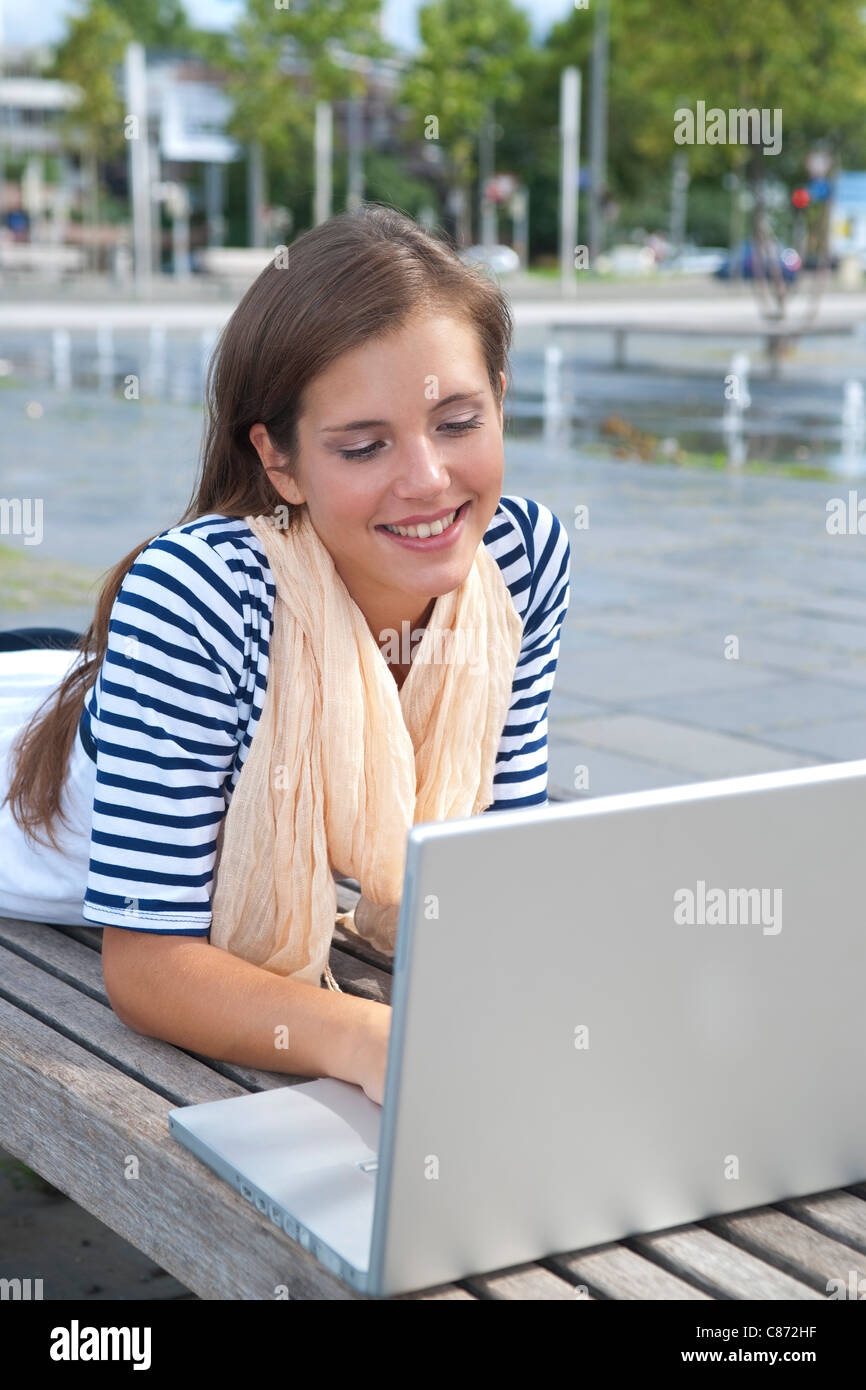 Preteen girl lying on stomach using laptop computer Stock 