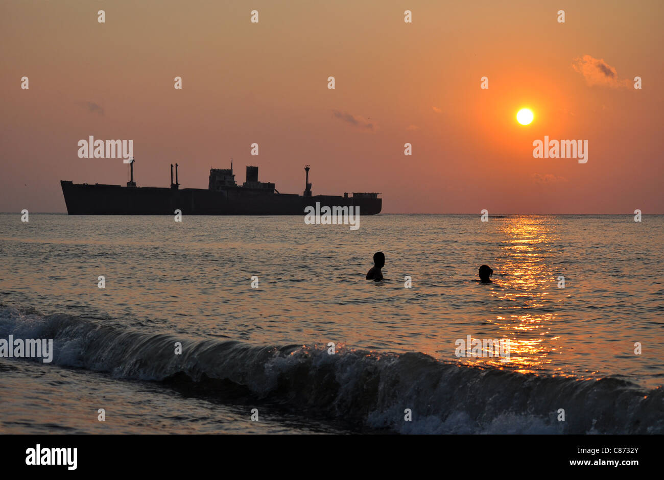 sunrise with a ship and swimmers, crock silhouette Stock Photo
