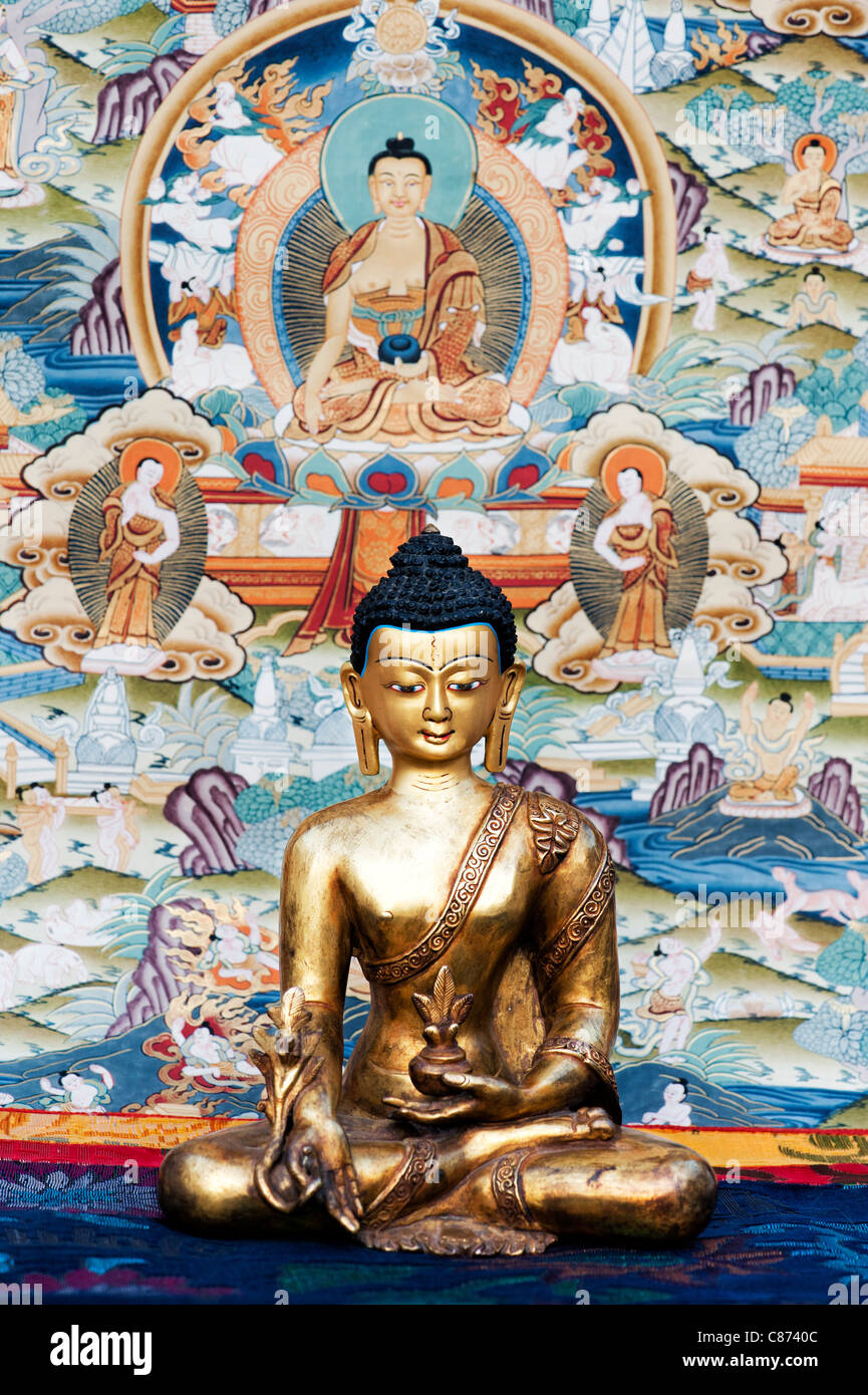 Buddha statue in front of a Tibetan Buddhist Thangka / Tanka painting Stock Photo