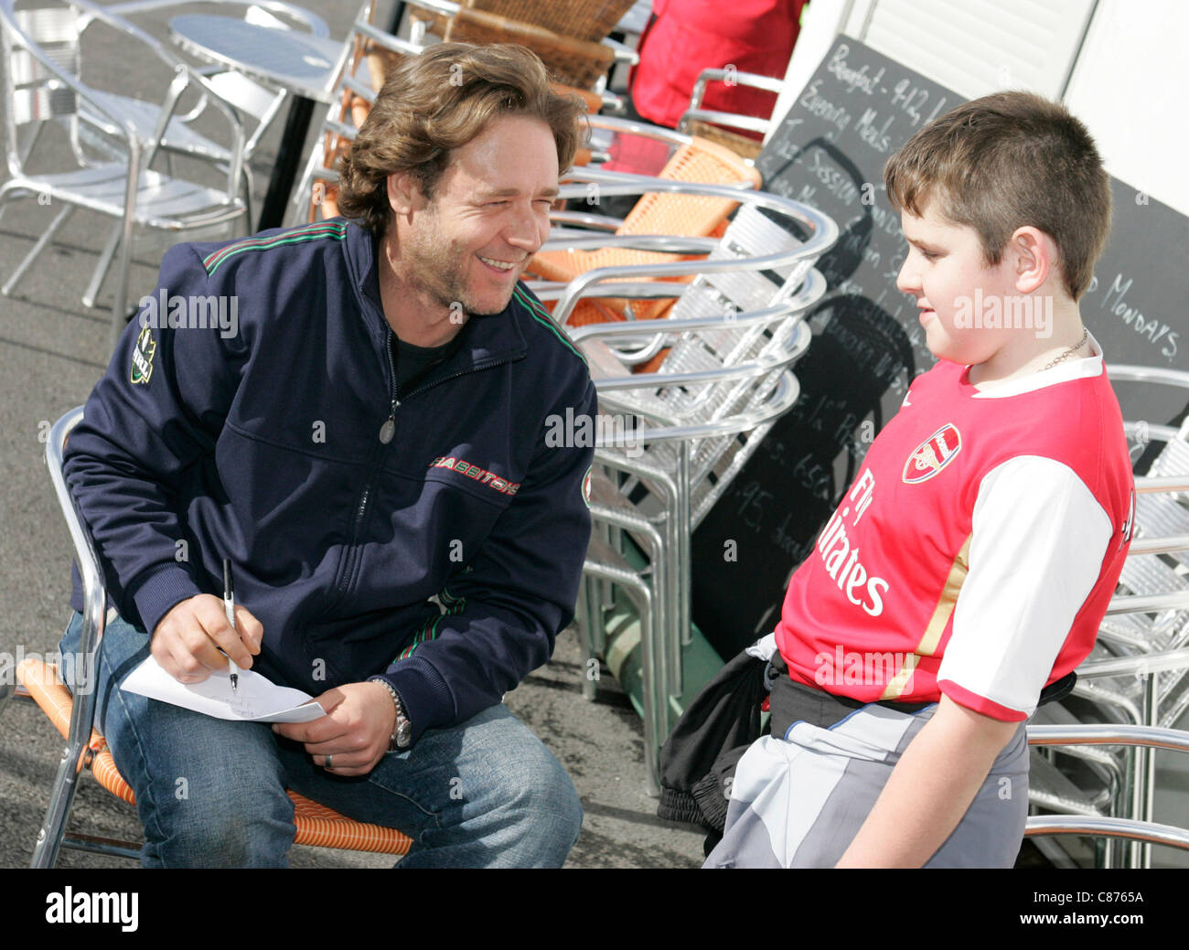 Russell Crowe chats with young arsenal football fan while signing autograph Stock Photo