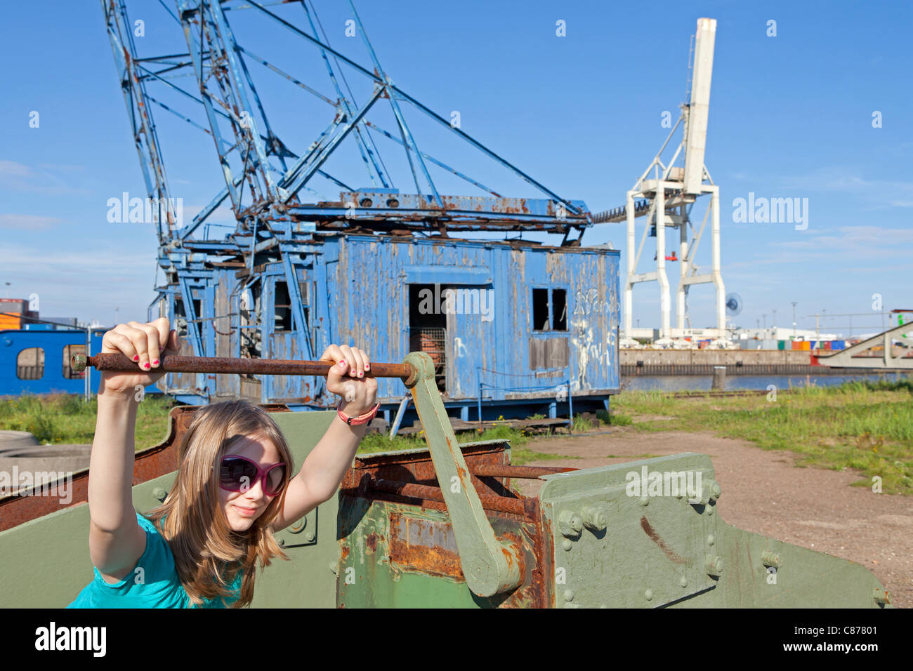 young girl trying to operate an old crank handle at the harbour museum, Hamburg Wilhelmsburg, Germany Stock Photo