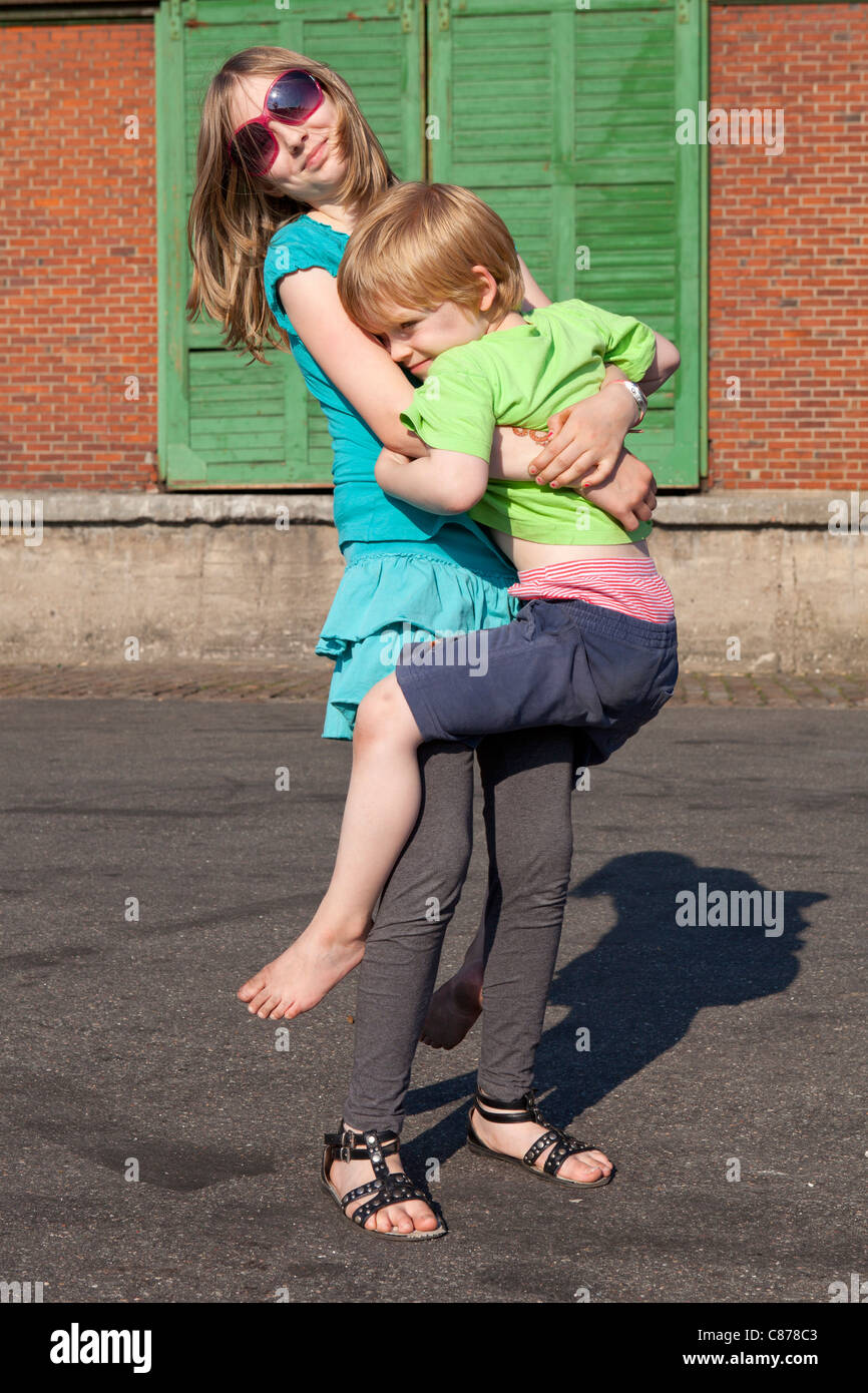 girl carrying her younger brother Stock Photo Alamy