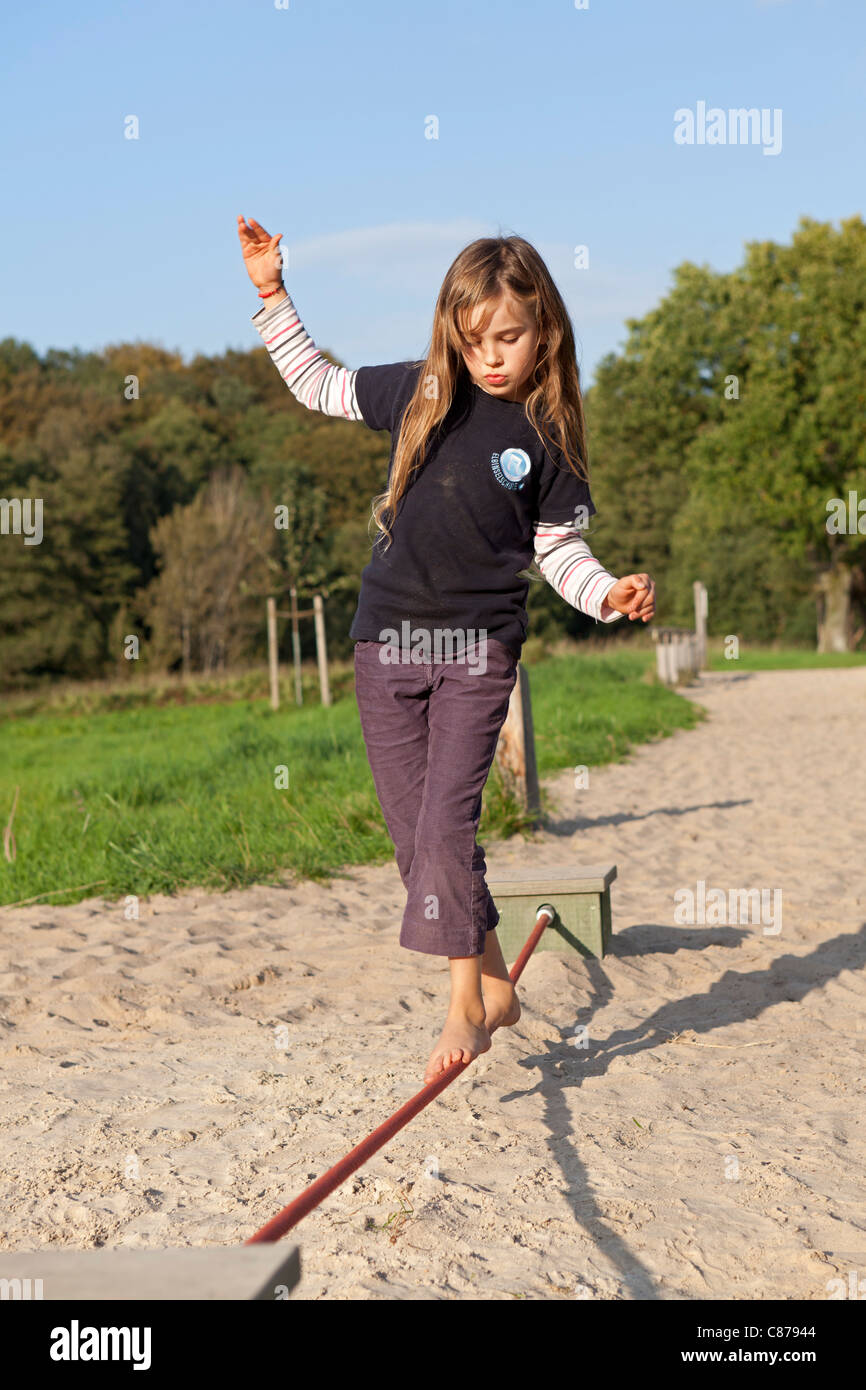 young girl balancing along a rope at barefoot park Egestorf, Luneburg Heath, Lower Saxony