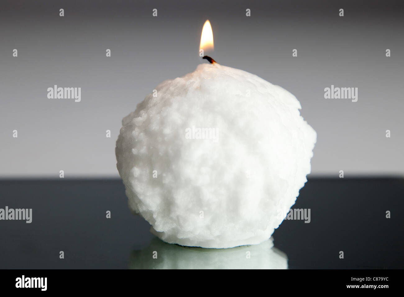 A snowball candle, placed on a mirror plate to give an abstract