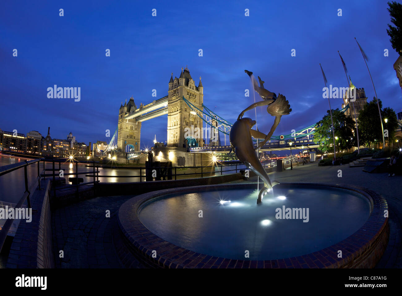 Girl With A Dolphin, statue by David Wynne, illuminated at night in front of Tower Bridge,  London, England, UK, United Kingdom, Stock Photo