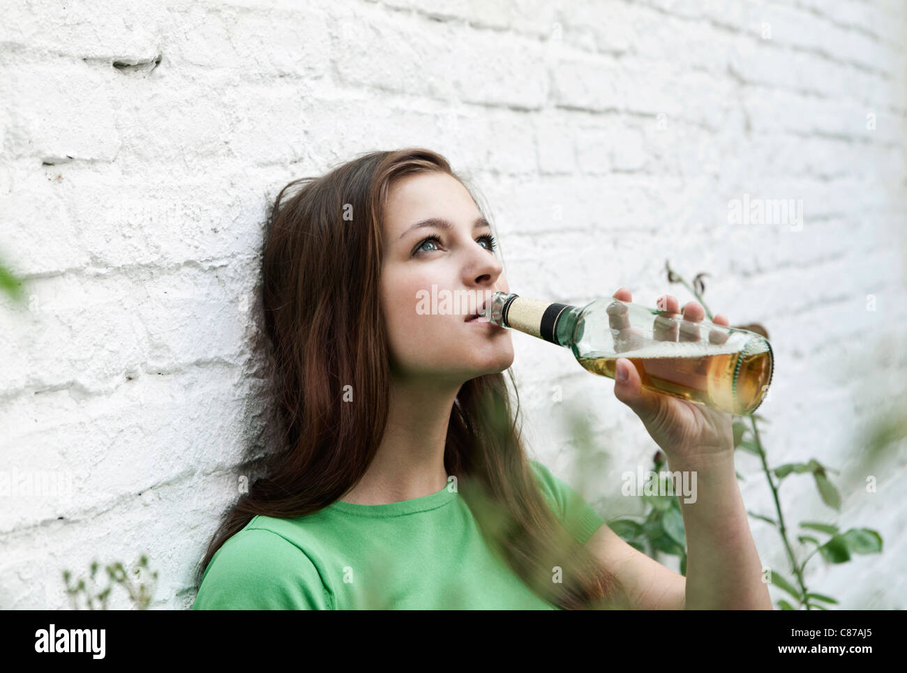 Germany, Berlin, Young woman drinking beer from beer bottle Stock Photo