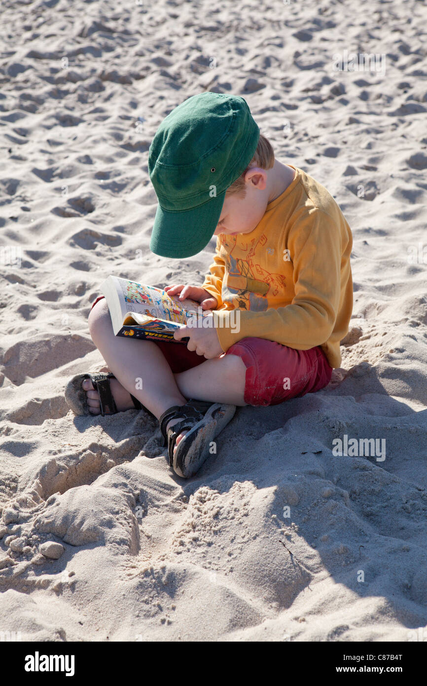 portrait of a young boy reading at a beach Stock Photo