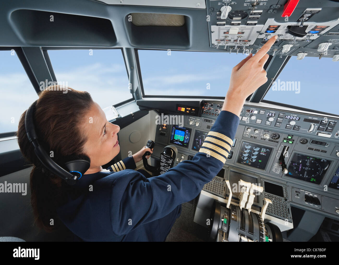 Germany, Bavaria, Munich, Woman flight captain piloting aeroplane from airplane cockpit Stock Photo