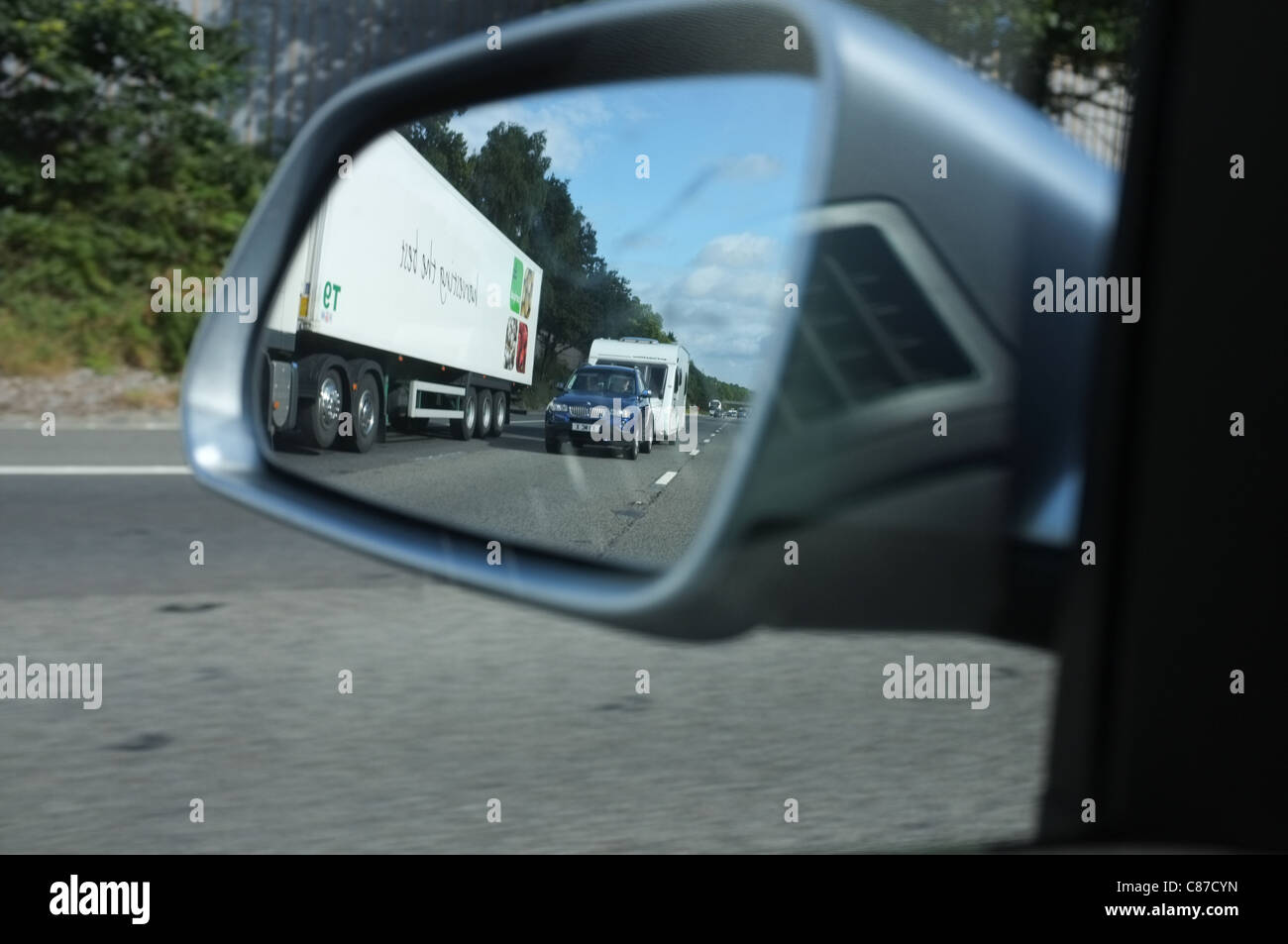 A car towing a caravan down the motorway reflected in a car wing mirror Stock Photo