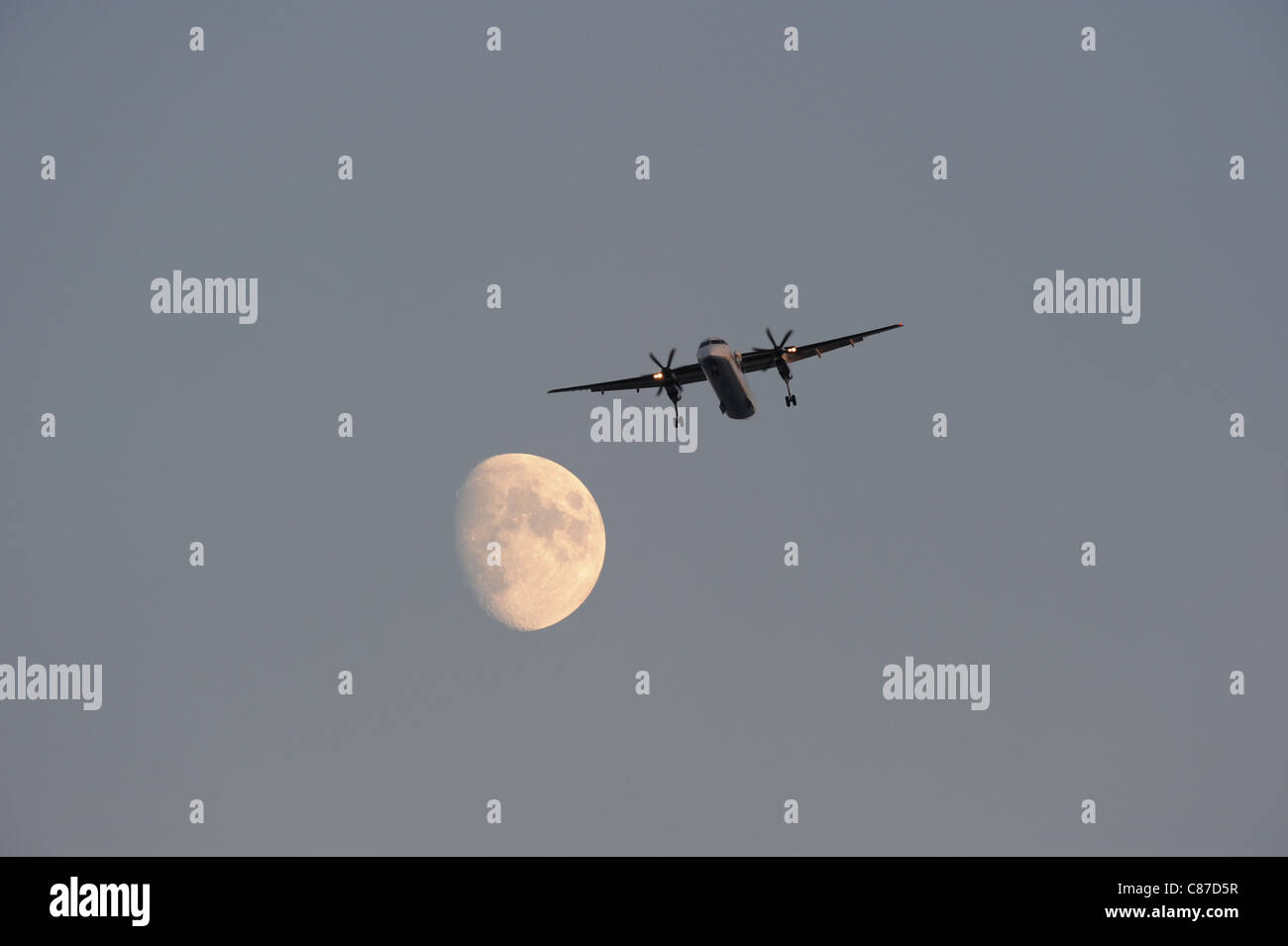 propeller aeroplane flies past the moon Stock Photo