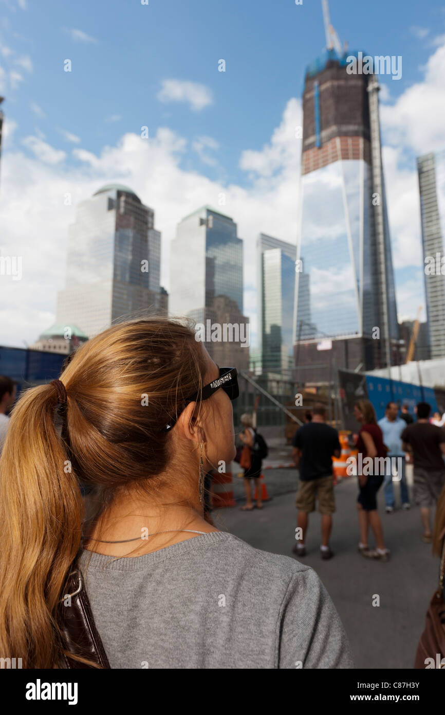A woman looks at the rising Freedom Tower (One World Trade Center), while standing by the entrance to the National September 11 Memorial in New York. Stock Photo