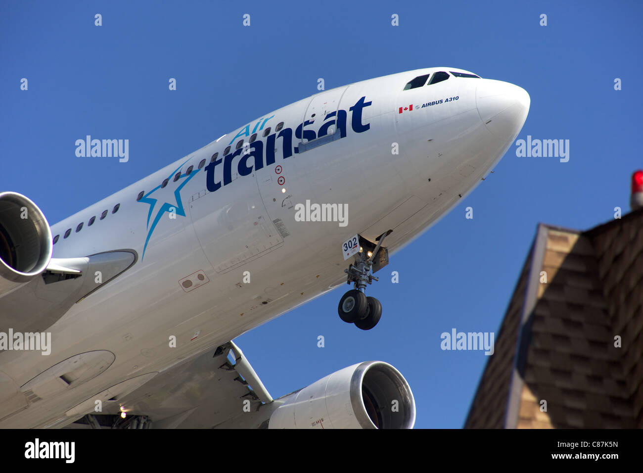 Air Transat A310 landing at Pearson Airport in Toronto flying over a building on final approach. Stock Photo