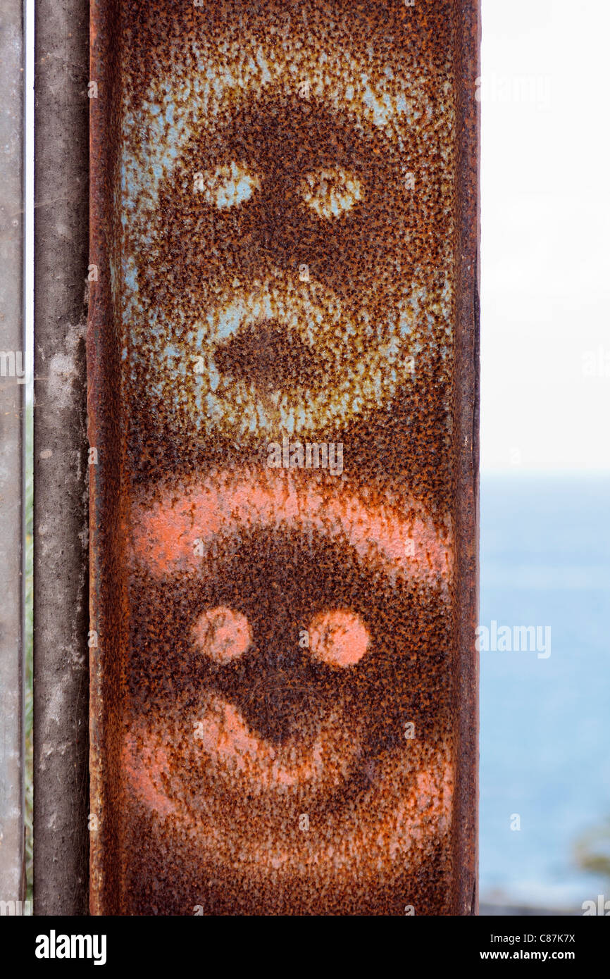 Graffiti smilies painted on a rusty iron gatepost Stock Photo