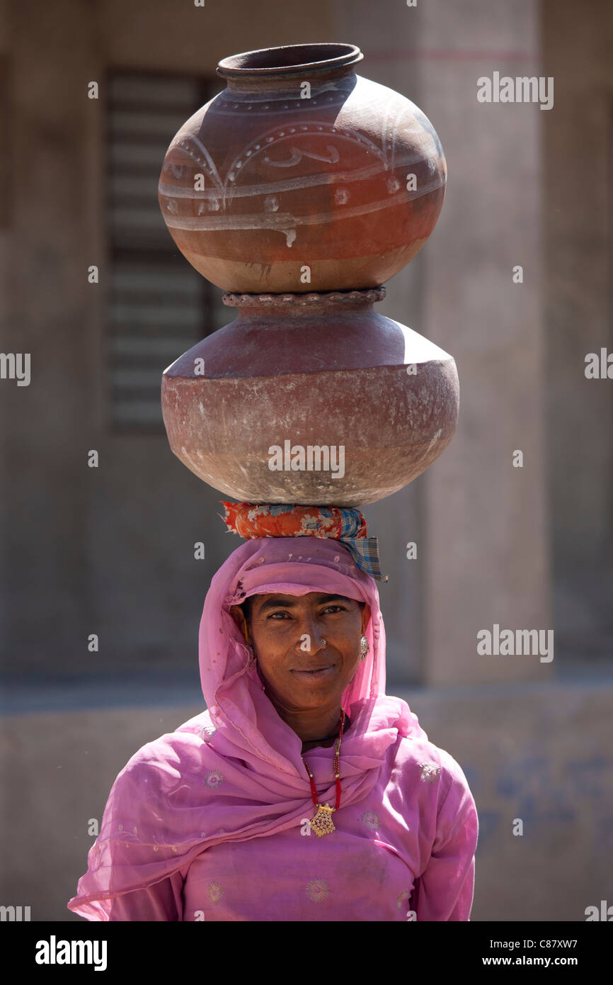 Indian woman in sari fetching water pots from well at Jawali village in Rajasthan, Northern India Stock Photo