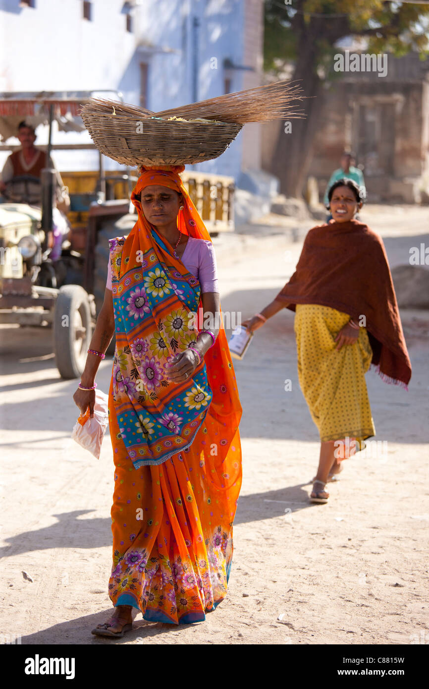 Young Indian woman carrying grain crop in Narlai village in Rajasthan, Northern India Stock Photo