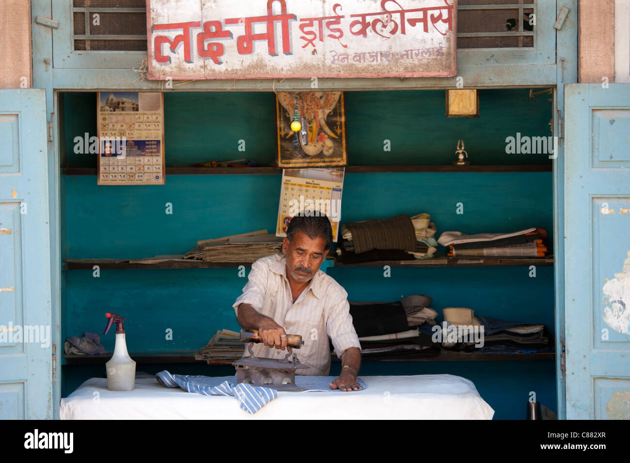 Indian man pressing clothes in his workroom in Narlai village in Rajasthan, Northern India Stock Photo