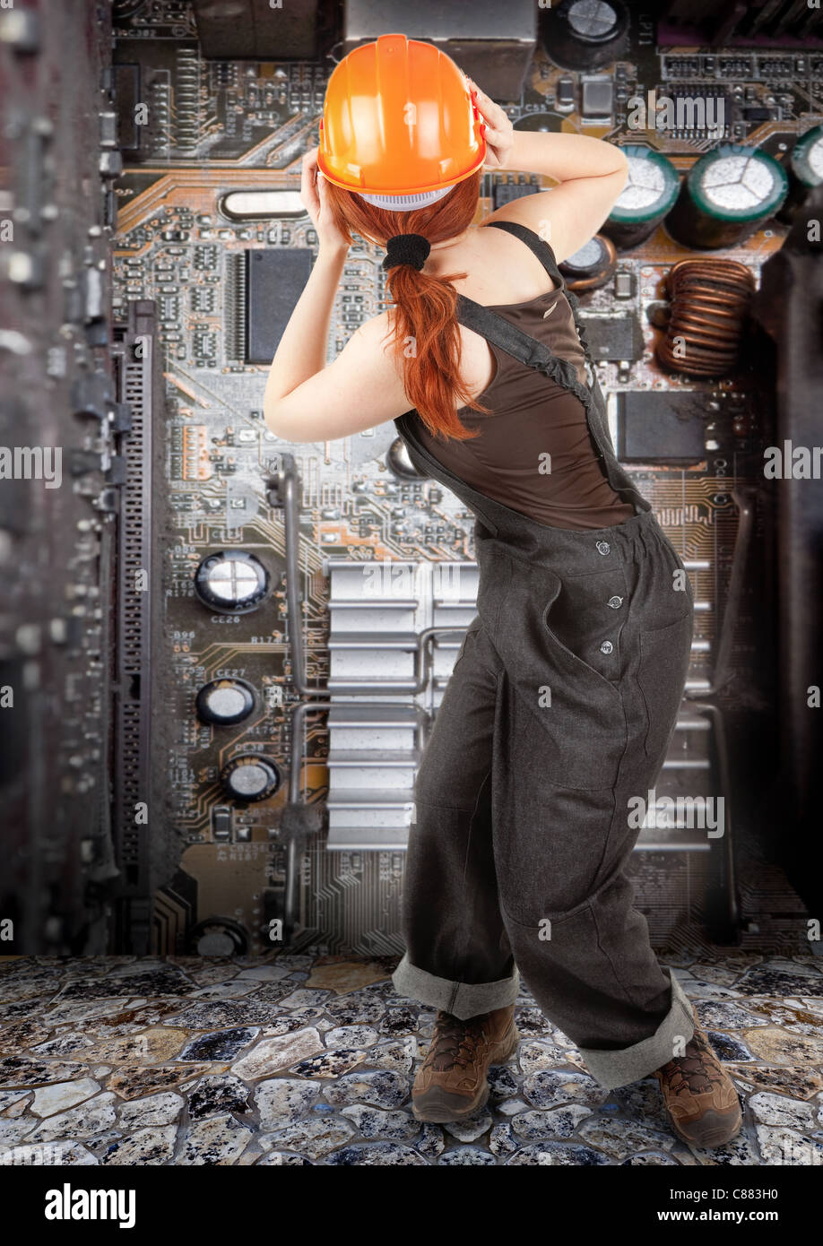 portrait of red haired girl in overalls on background of old electronic circuit boards Stock Photo