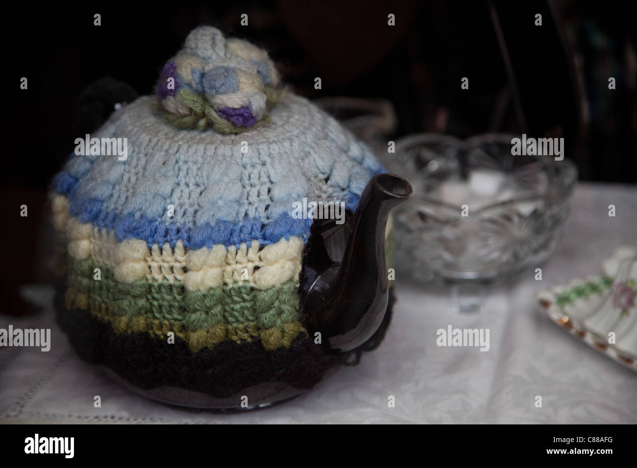 Brown china teapot with old knitted tea cosy and sugar bowl Stock Photo