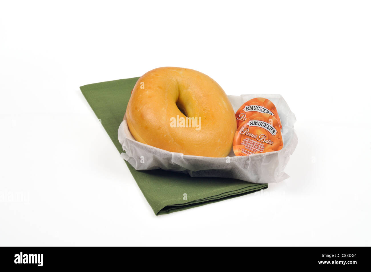 Plain bagel with 2 smuckers peanut butter containers  in a paper basket  with green napkin on white background, cutout. Stock Photo