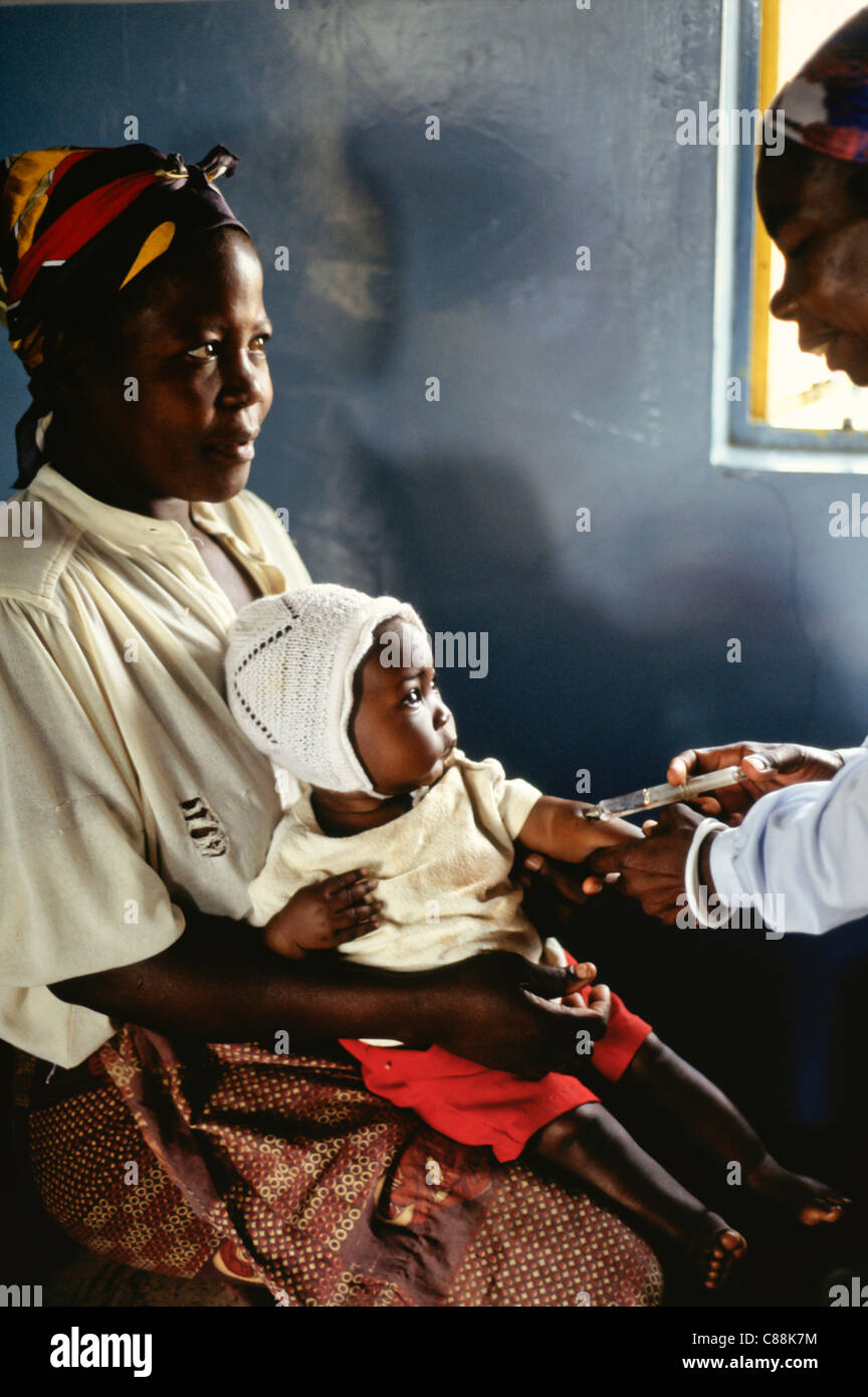 Mbati, Zambia. Woman with her baby daughter receiving an innoculation injection at a rural medical post. Stock Photo