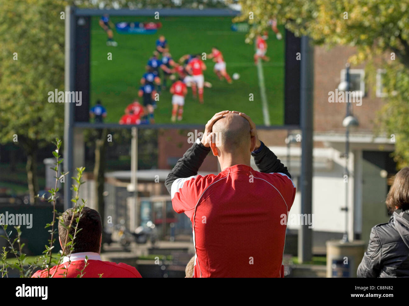 Swansea, UK, 15/10/2011. A Welsh rugby supporter reacts while  watching the closing stages of the RWC semi-final with France this morning, which they lost. They watched the match on a large outside television screen in Castle Square in the centre of Swansea. Stock Photo