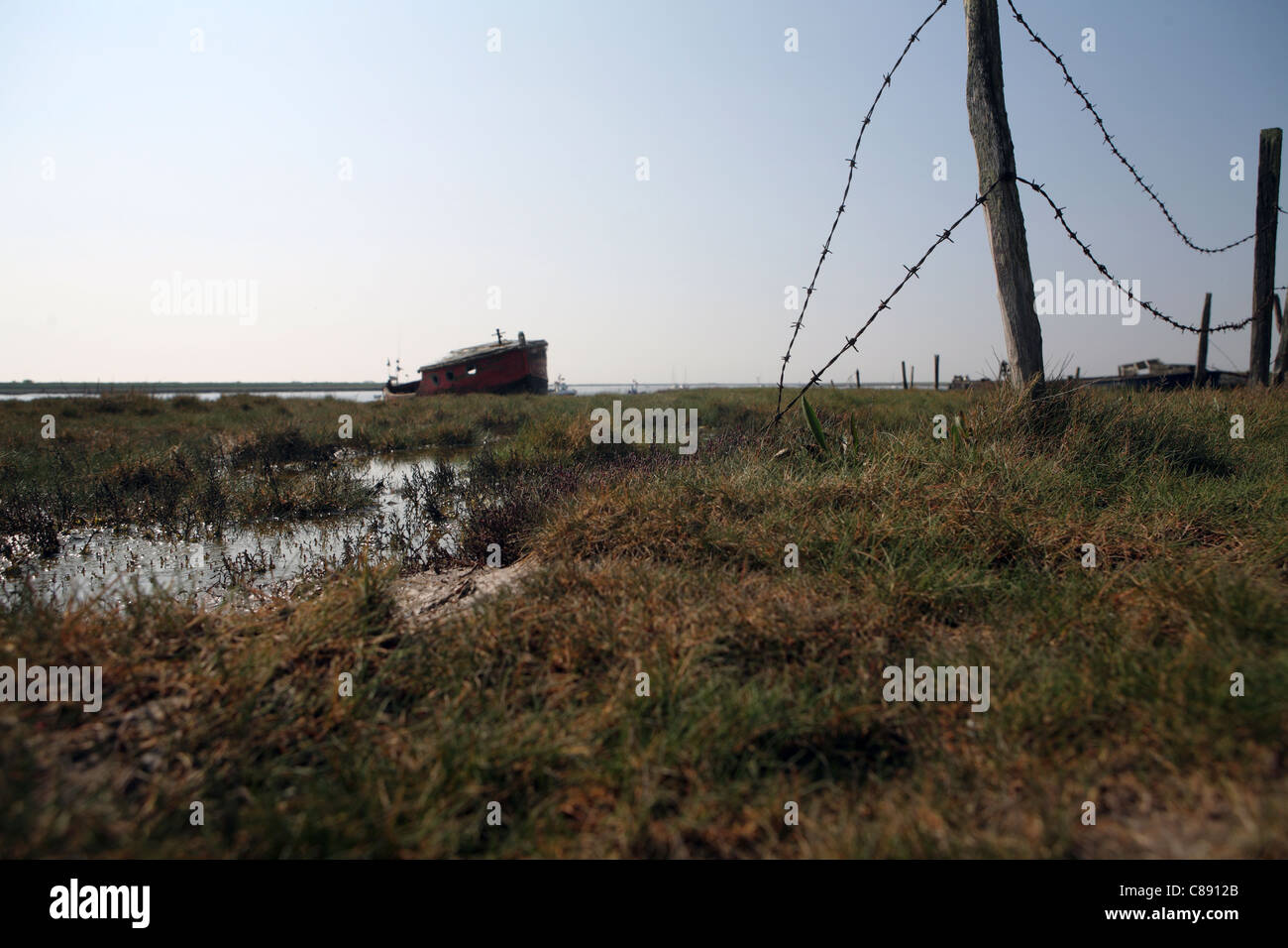 River Ore / Alde, bank / wall at Orford Suffolk, UK showing abandoned boats in background Stock Photo