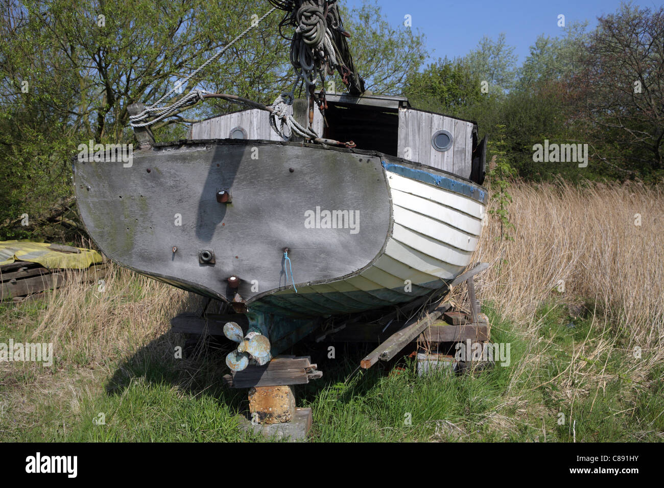 Abandoned wooden clinker built yacht in field boatyard, Orford, Suffolk, UK Stock Photo