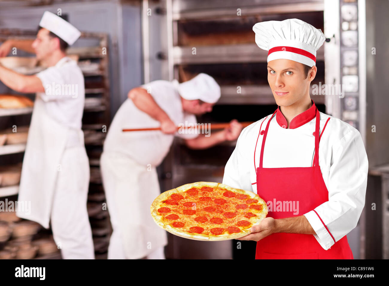 A male baker holding freshly baked pizza in bakery Stock Photo Alamy