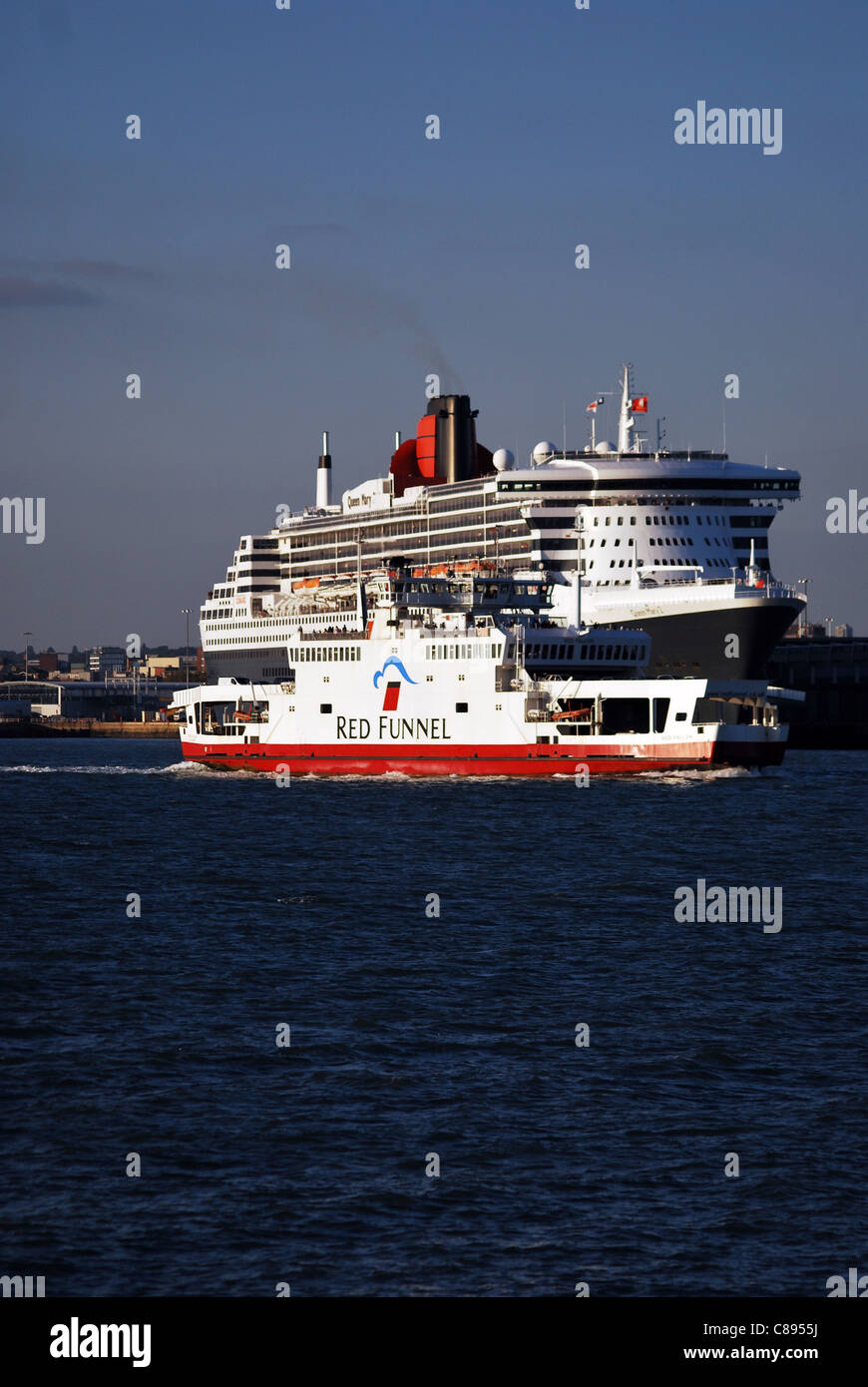 The Isle of Wight car ferry 'Red Falcon' operated by Red Funnel passes the cruise liner Queen Mary 2 in Southampton. Stock Photo
