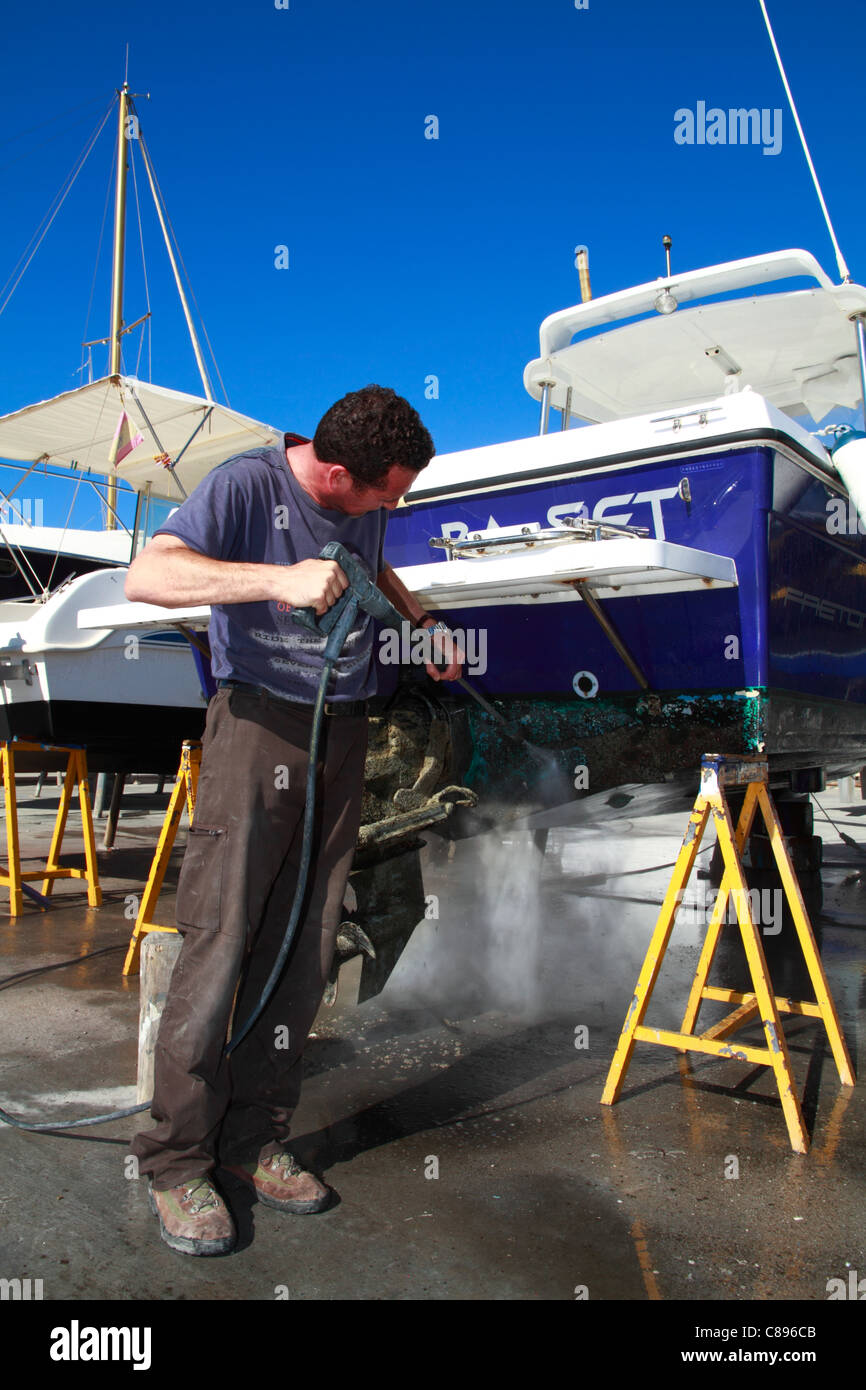 Seaman cleaning his boat´s hull with high pressure water pistol Stock
