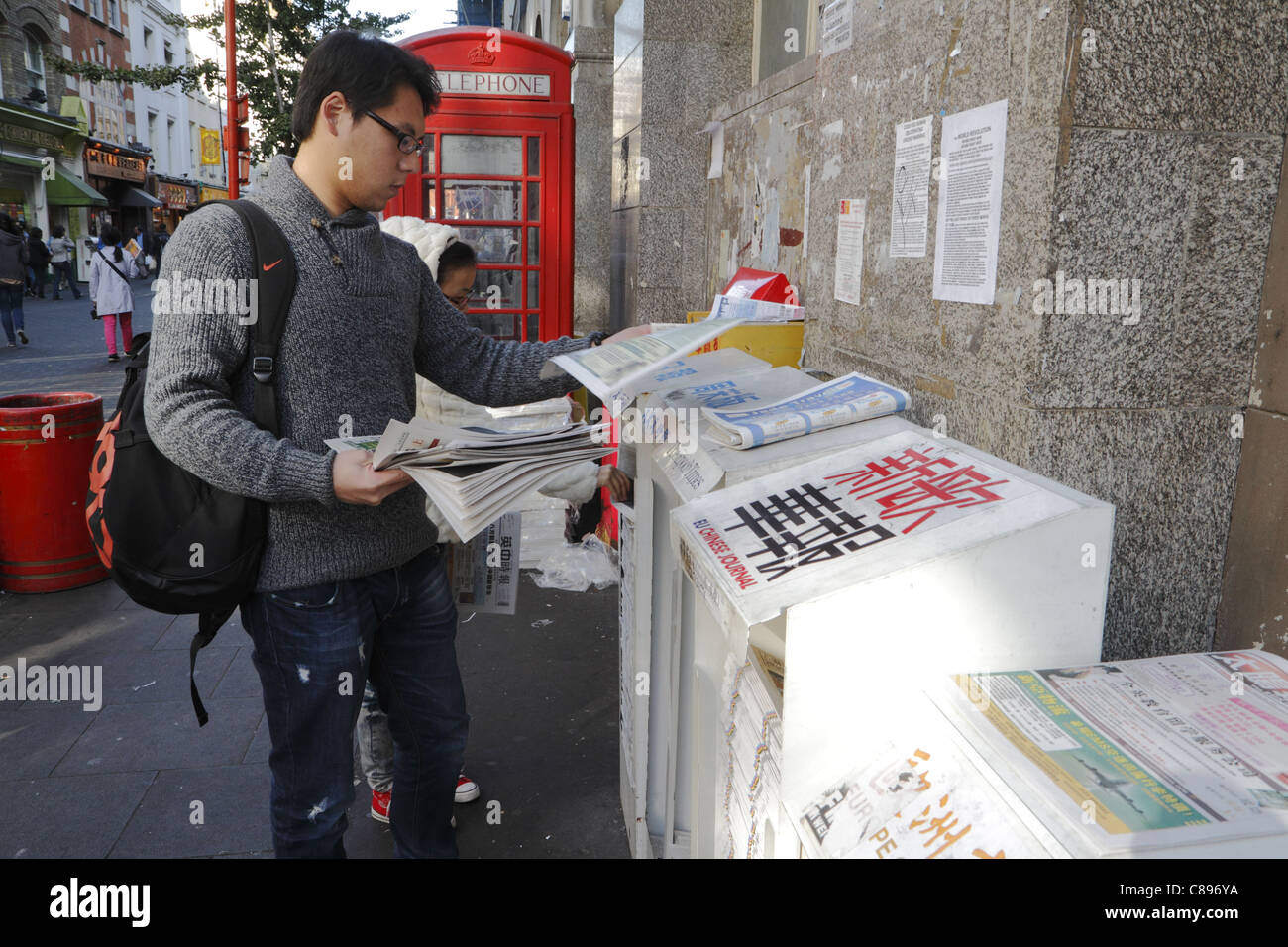 Young Chinese man at newspaper stand, Gerrard street, London, UK Stock Photo
