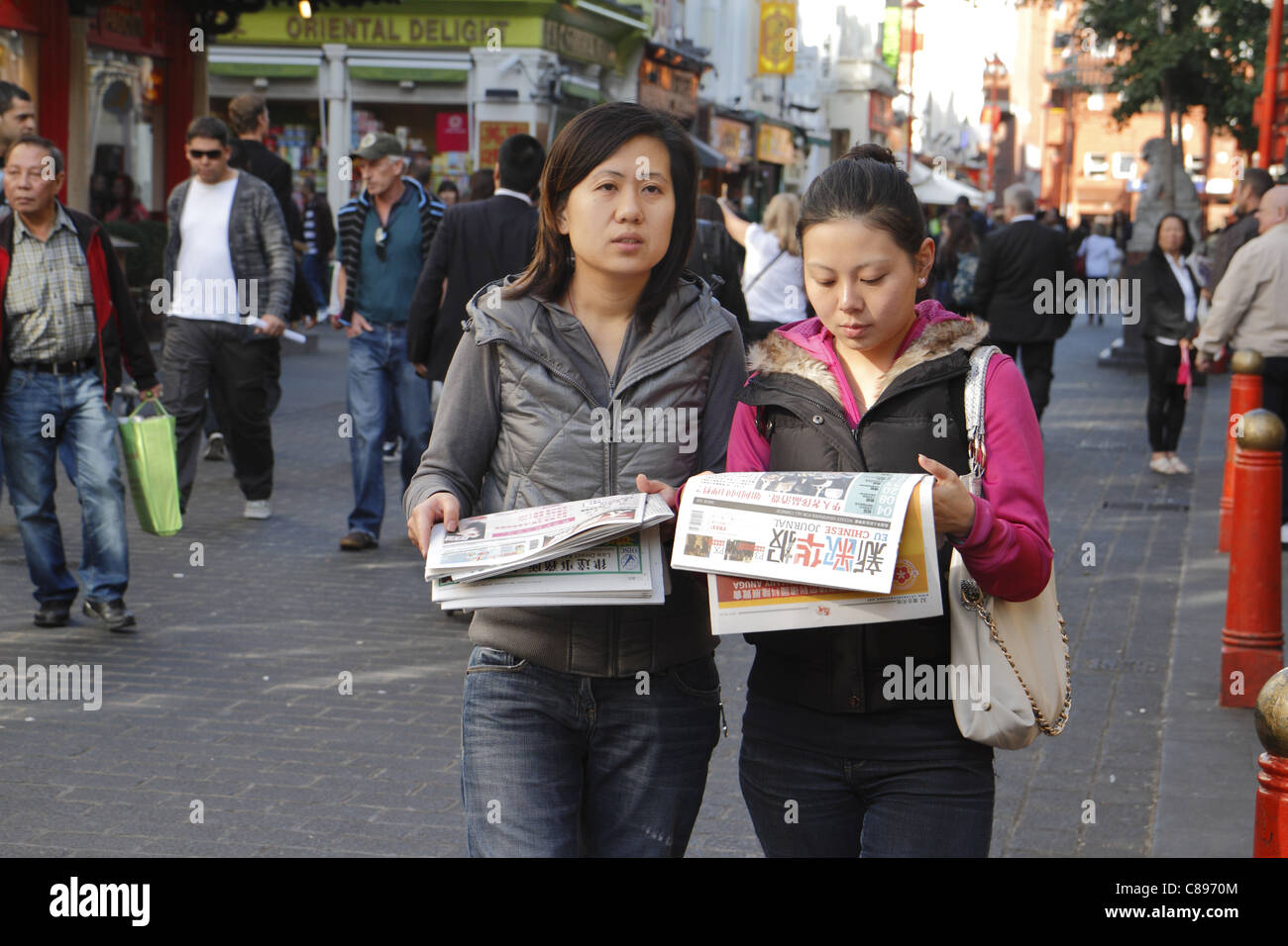 Two young Chinese women reading newspapers, Gerrard street, London UK Stock Photo