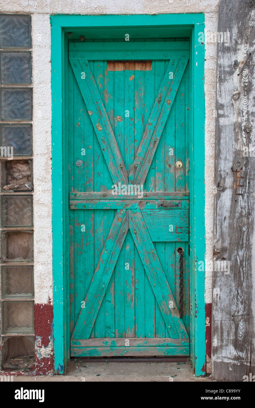 An old green door conceals unknown property in an abandoned building in Ft. Sumner, New Mexico. Stock Photo