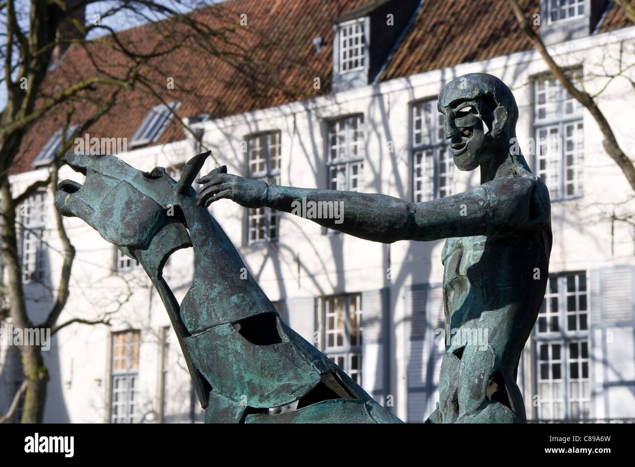One of Four Horsemen of the Apocalypse bronze sculptures by Rik Poot (+ Arentshuis), Hof Arents (Square) central Bruges, Belgium Stock Photo