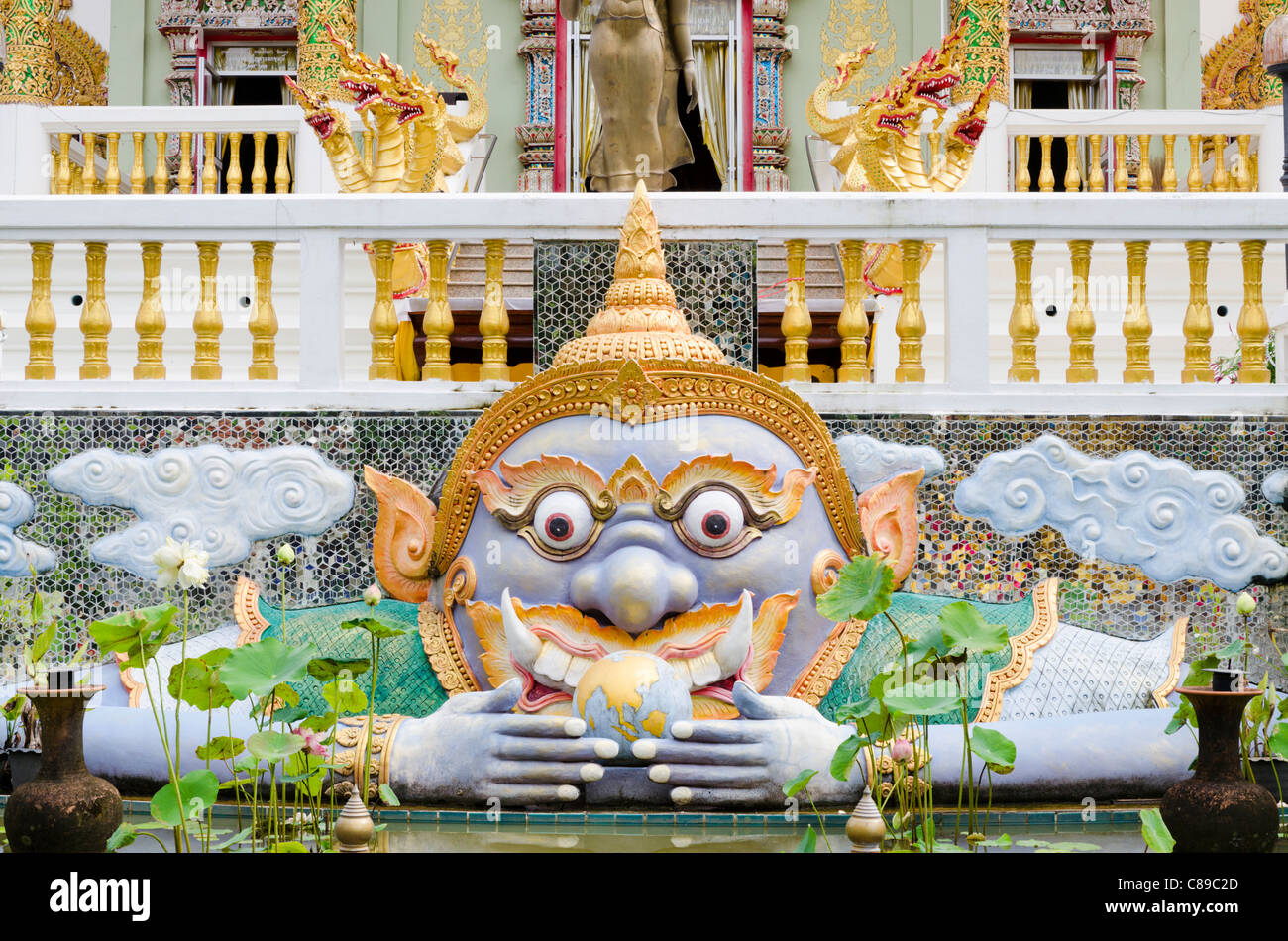 Large colorful statue of Buddhist deity Kala with bulging eyes in front of temple in northern Thailand Stock Photo