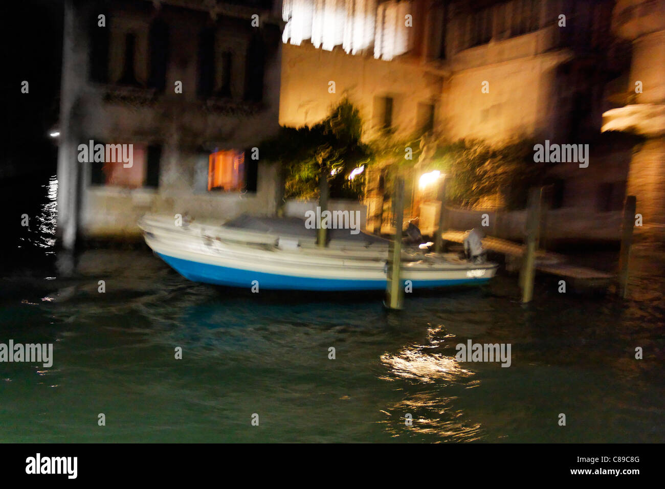 Anchored Venice boats in the night, blurred by the moving on the waves - a concept shot full of atmosphere. Stock Photo