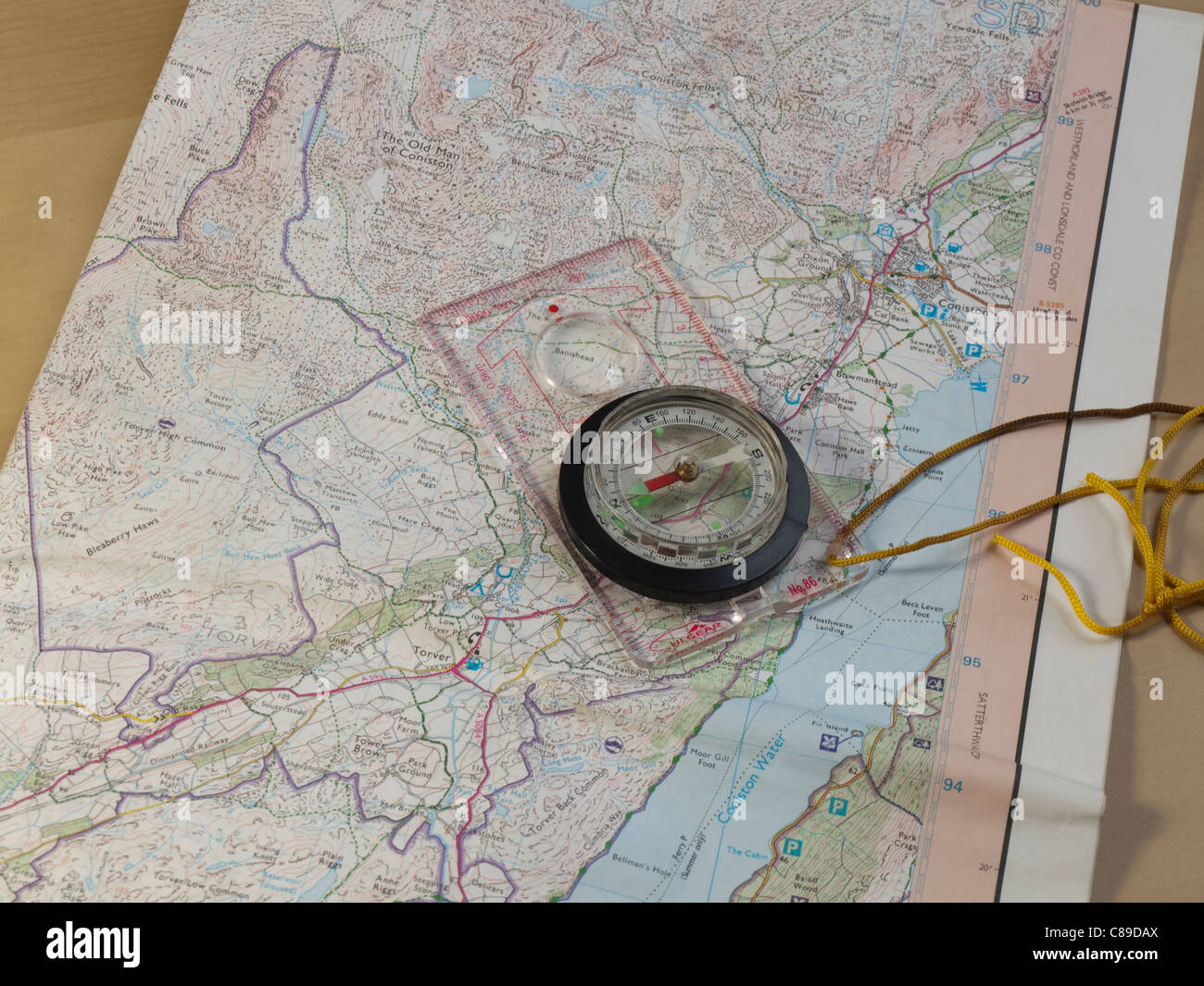Ordnance survey map of the area of Coniston in the English Lake District with a hiker's compass on a table. Stock Photo